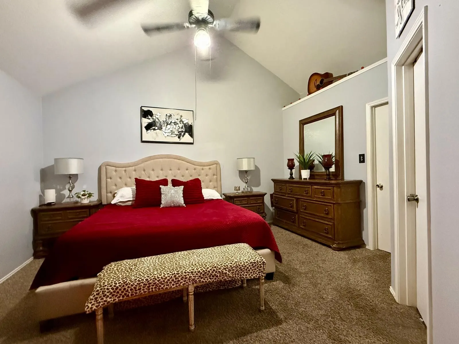Vaulted ceiling with a ceiling fan, plush carpet flooring, and a neutral wall color
