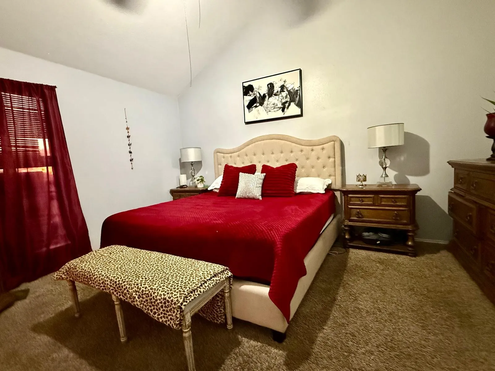 Vaulted ceiling, tufted headboard, window with blinds, ceiling fan, and carpeted flooring