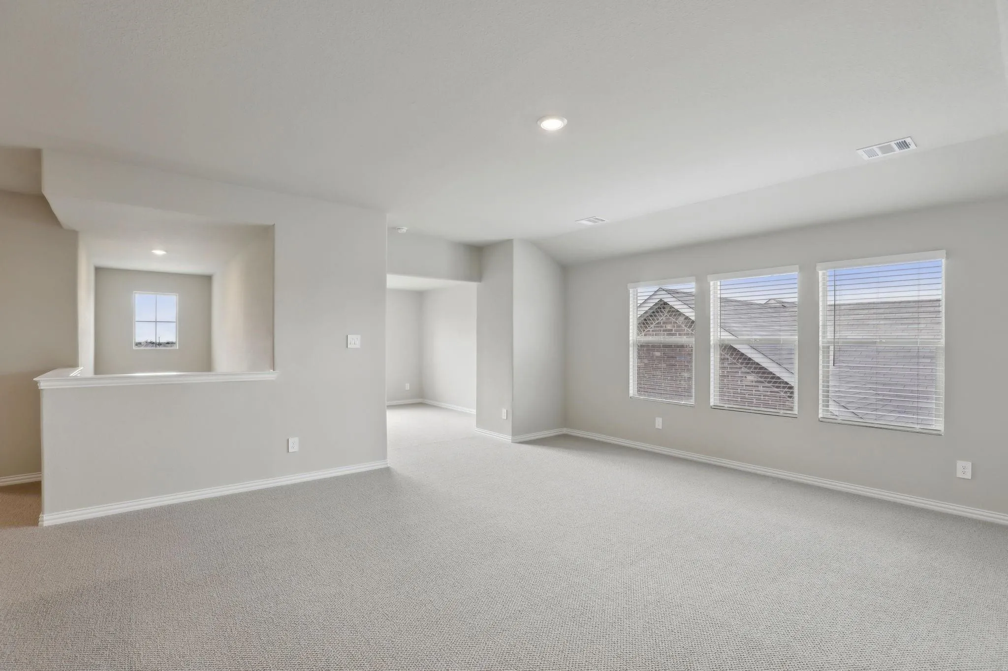 Expansive carpeted area with recessed lighting and multiple windows