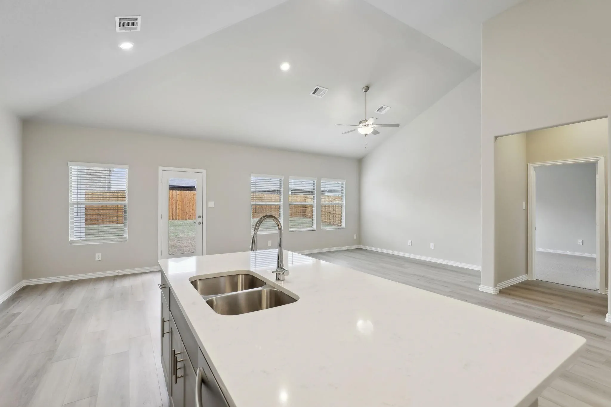 Kitchen island with an undermount double basin sink, stainless steel faucet, and light-toned countertop
