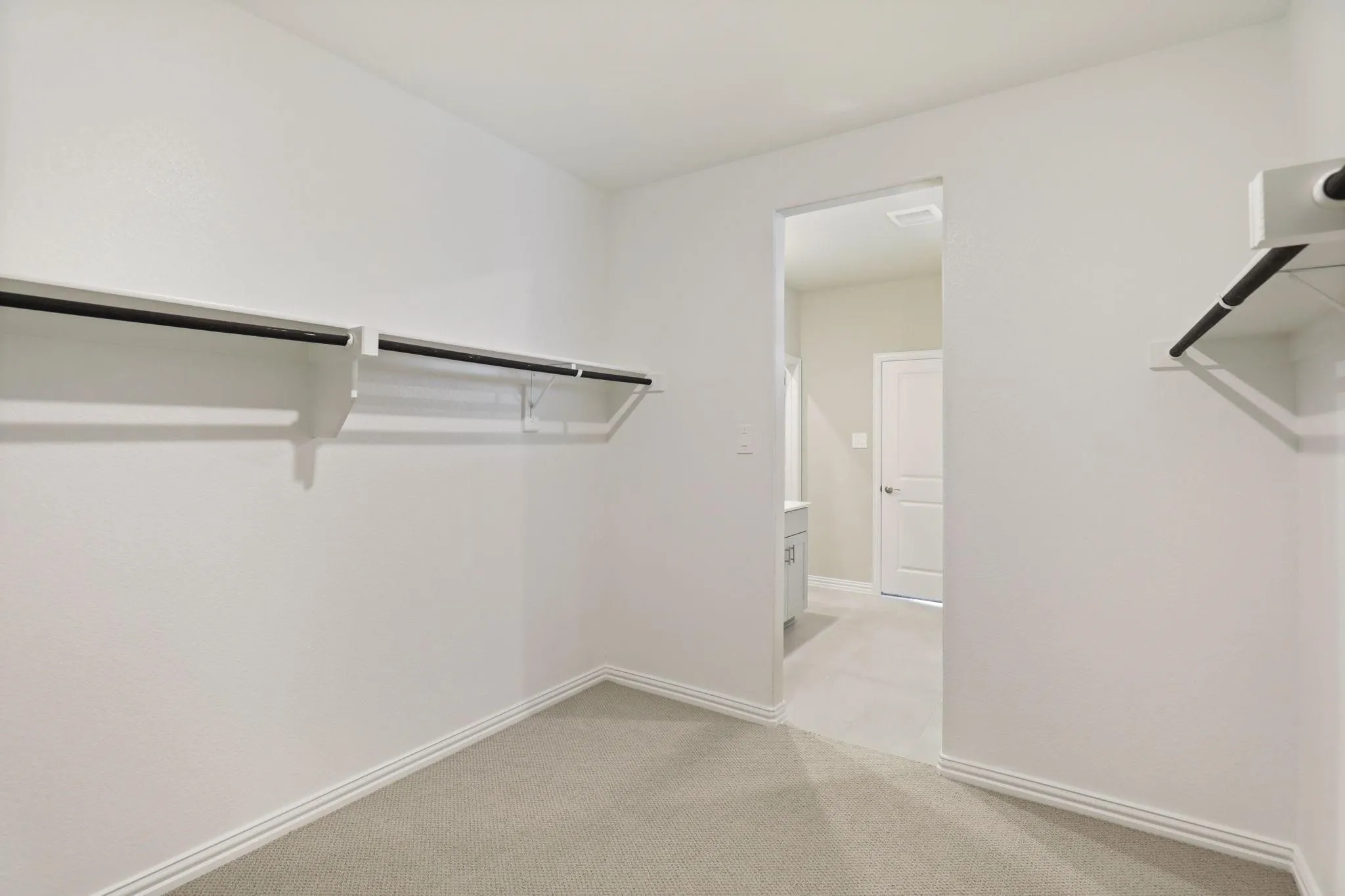 Carpeted interior with white walls, white trim, and built-in closet shelving