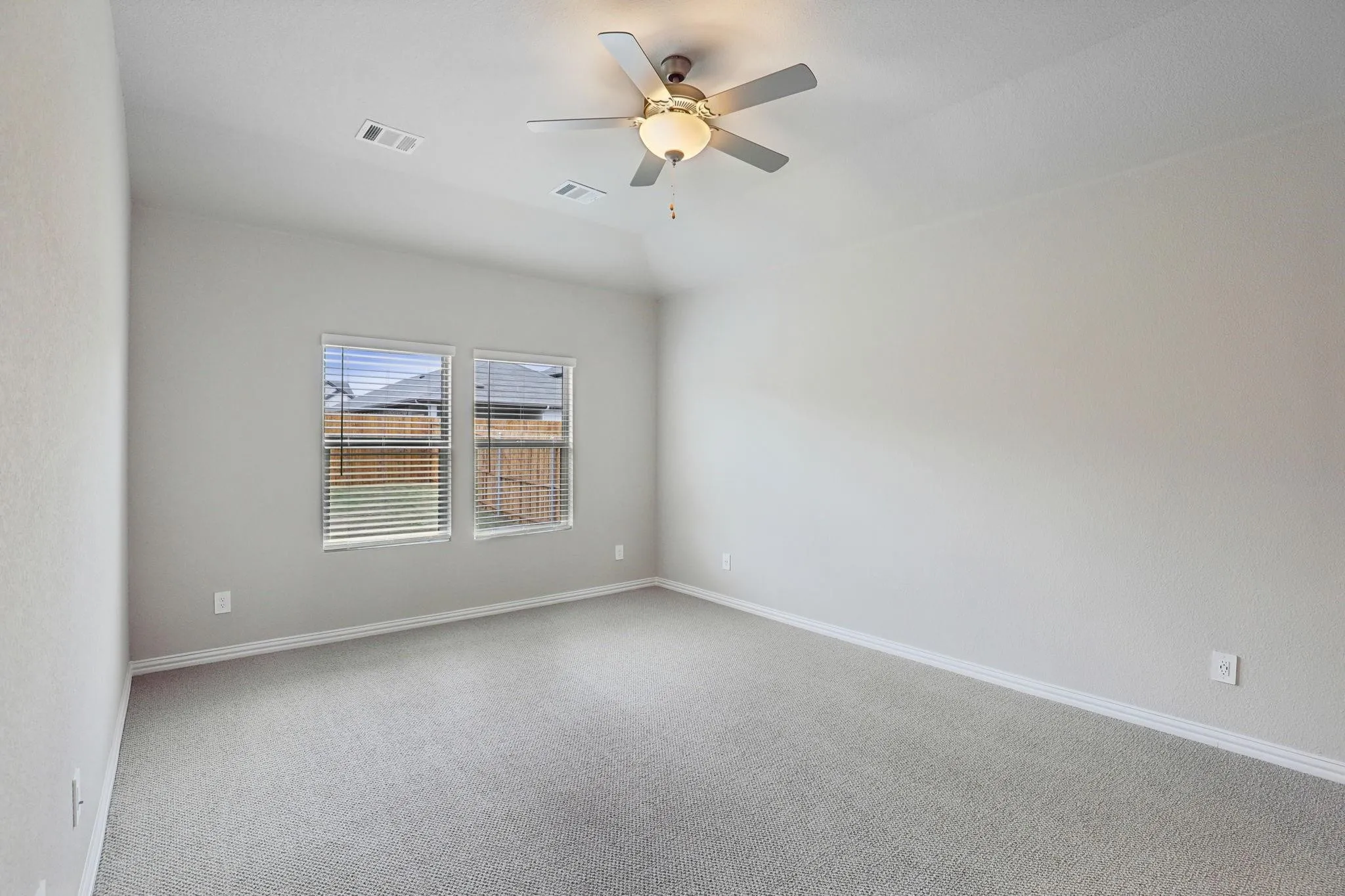 Light gray carpeting throughout, featuring two windows with horizontal blinds