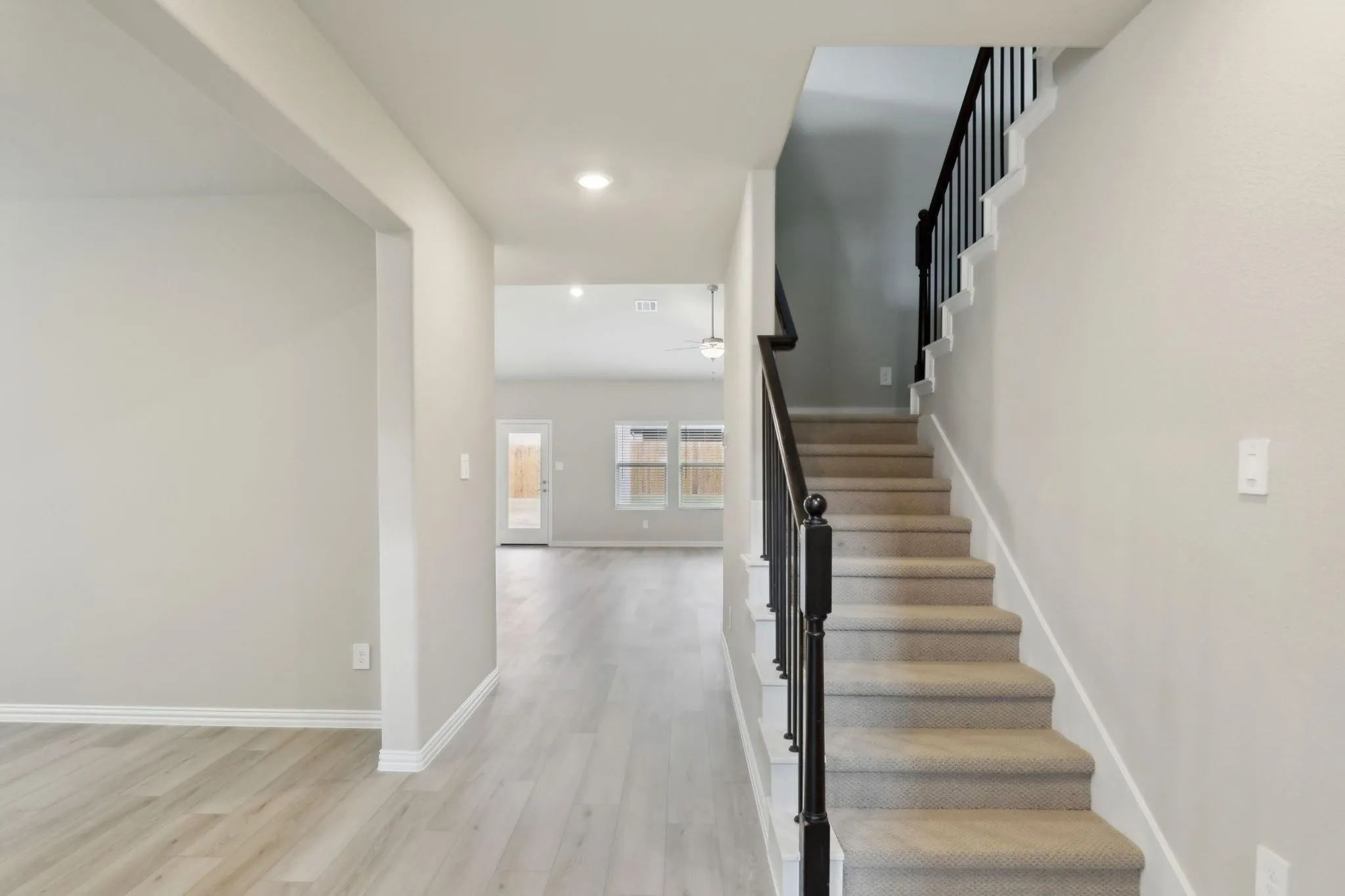 Staircase with carpeted treads and black iron balusters