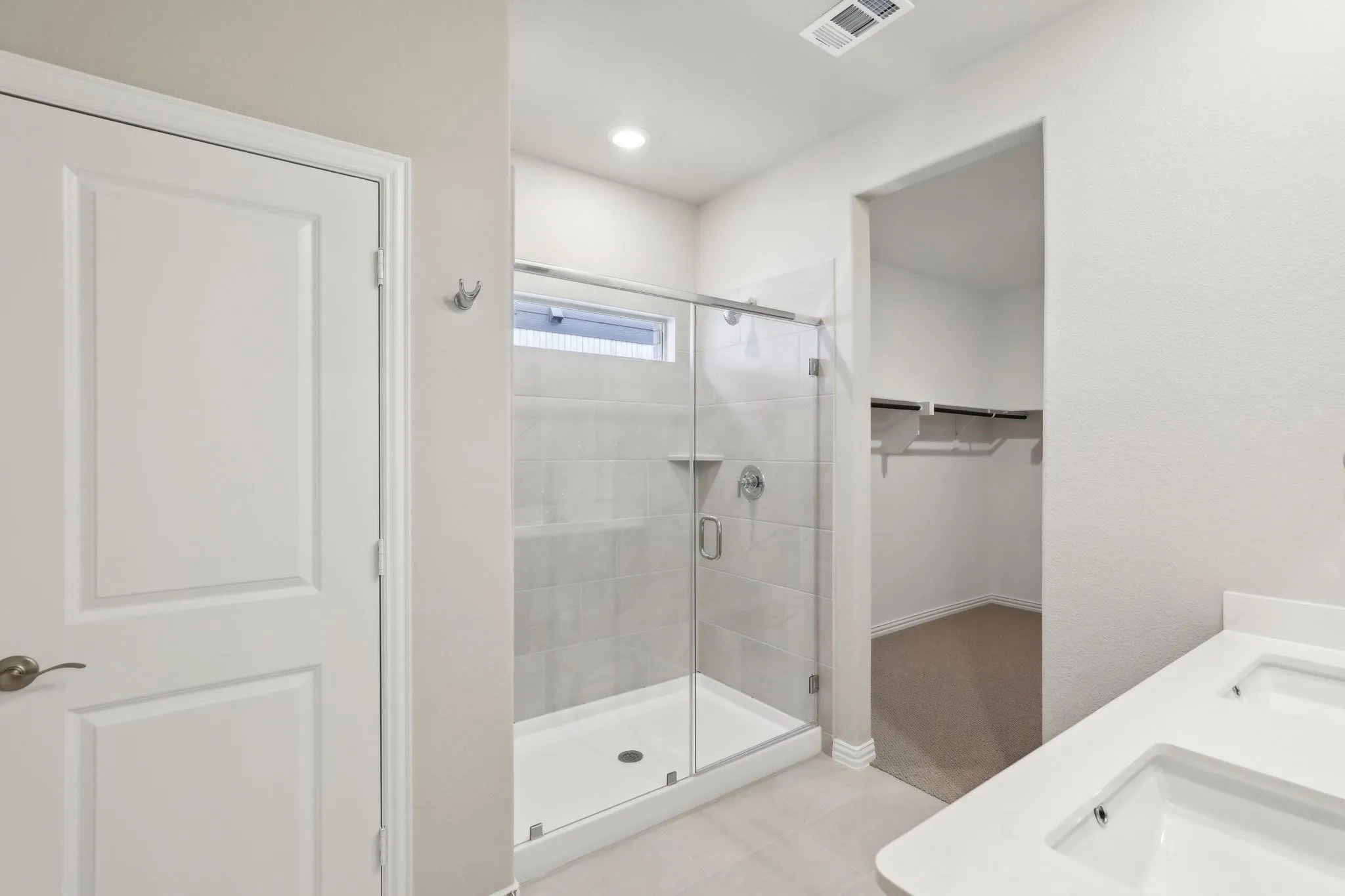 Walk-in shower with clear glass enclosure and tile surround