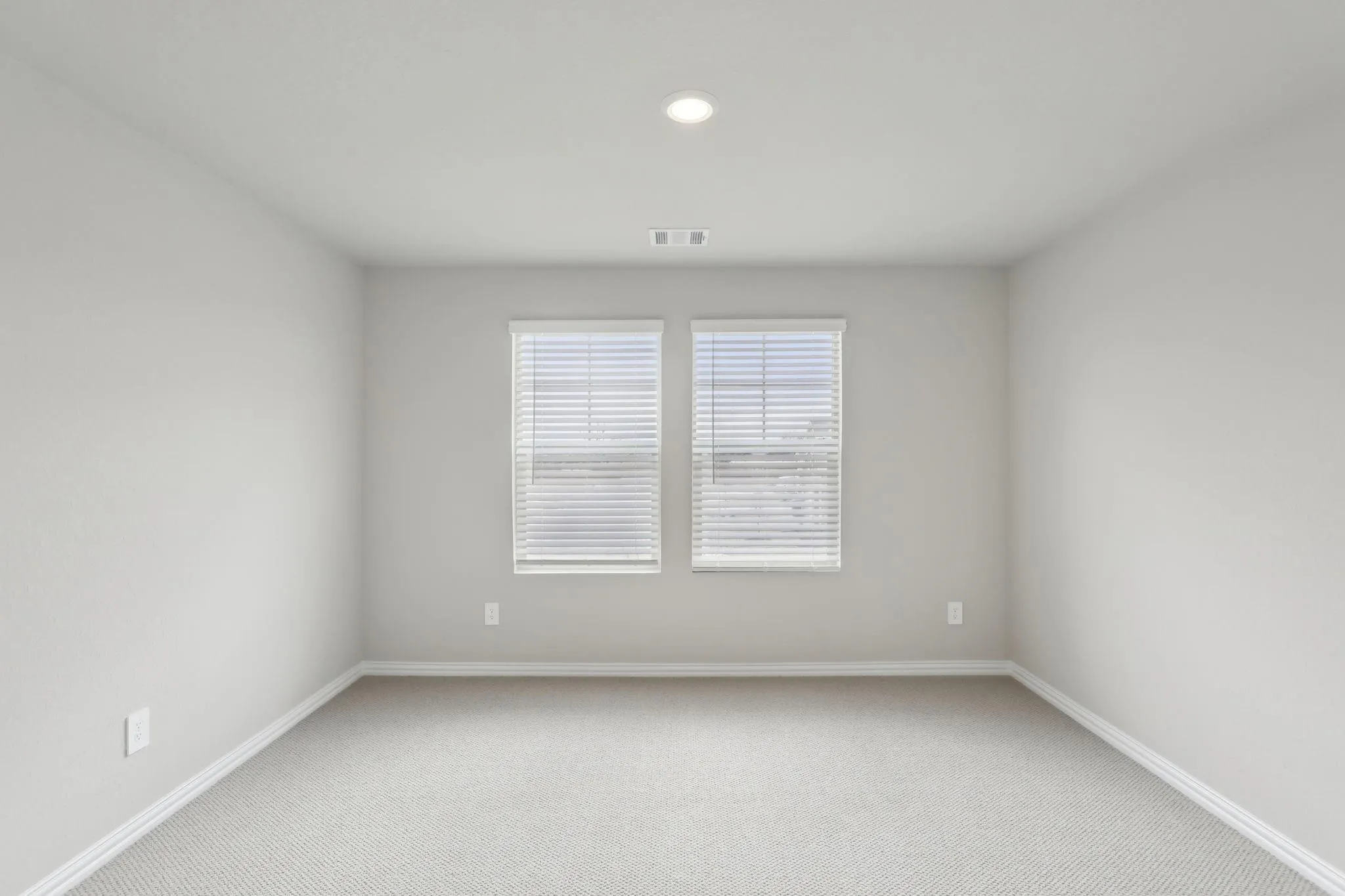 Light-colored textured carpeting and a recessed ceiling light