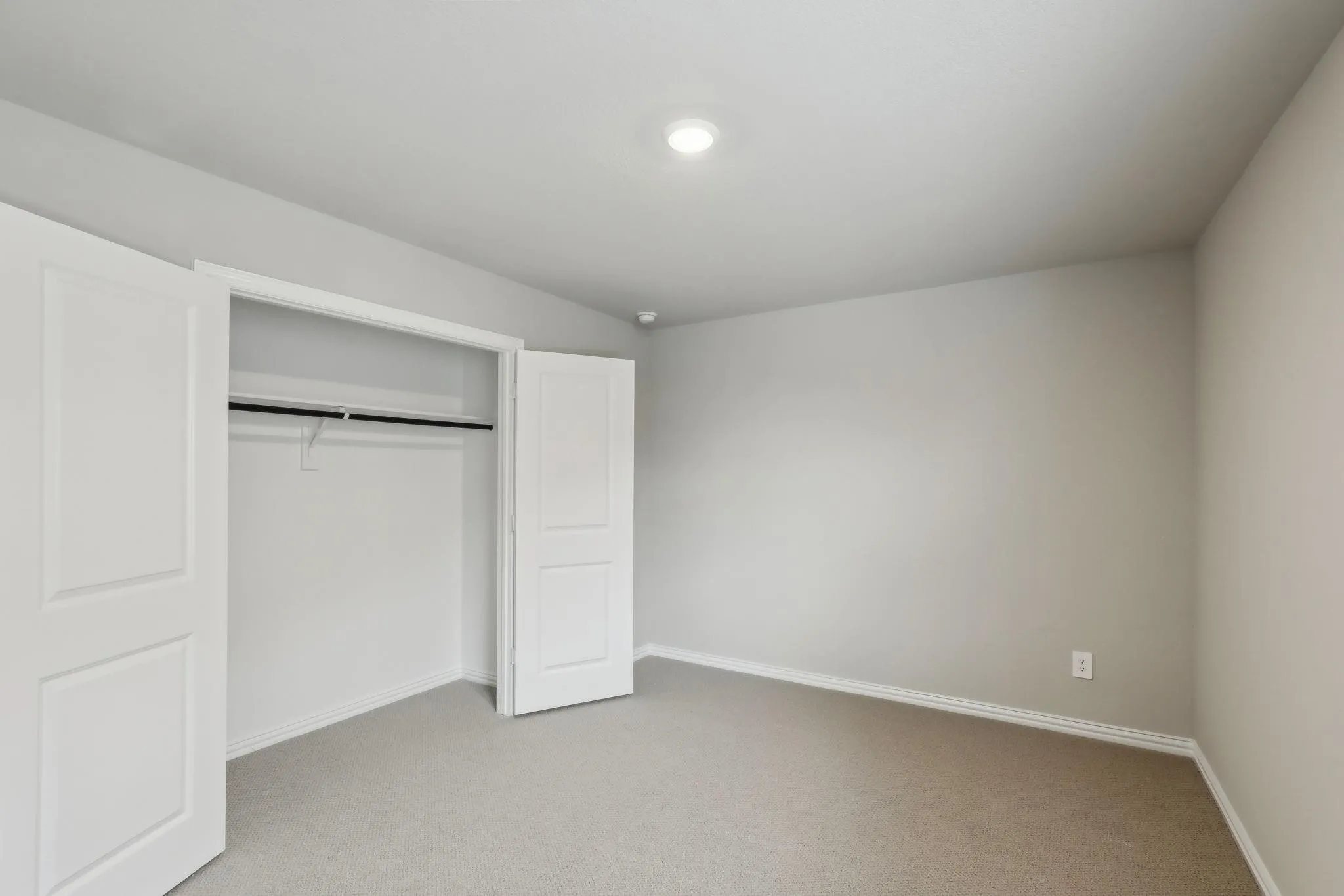 Neutral tone wall paint, recessed ceiling light, carpet flooring, bi-fold closet doors, and built-in closet rod