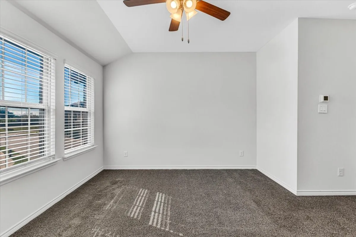 Neutral wall paint, two windows with blinds, ceiling fan, and carpeted flooring
