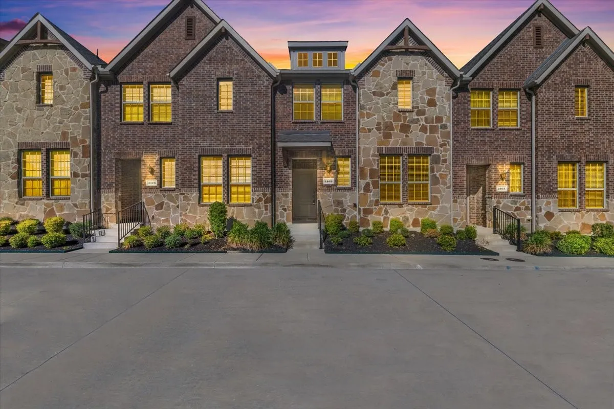 Brick and stone exterior featuring multiple gabled rooflines, decorative window grids, and structured landscaping