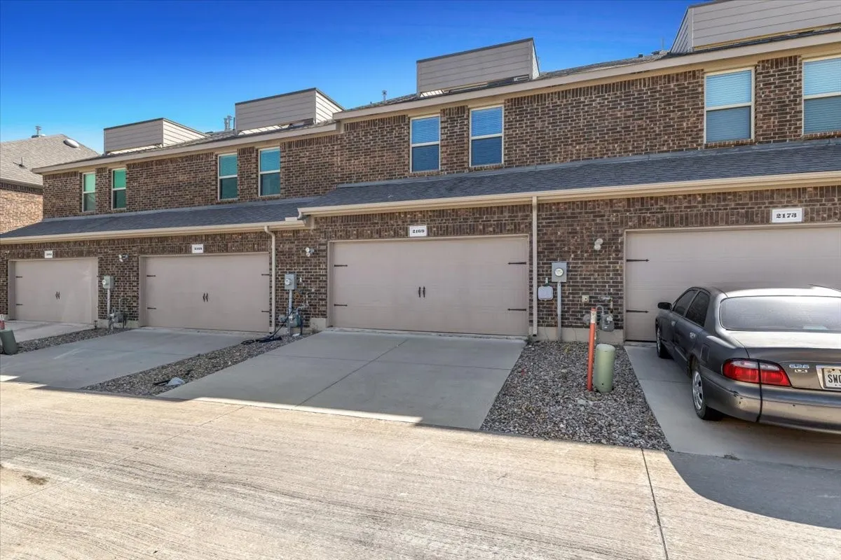 Brick exterior with multiple two-story units, individual garage doors, and concrete driveways