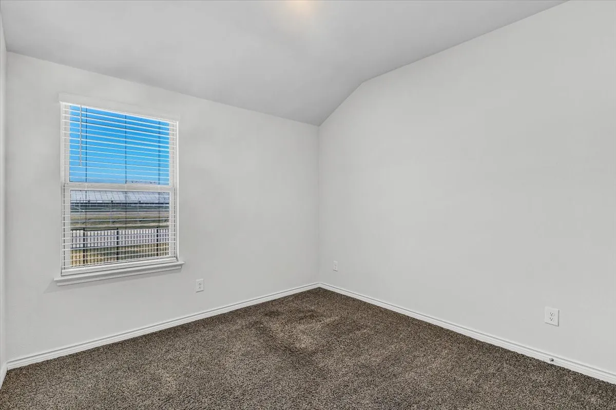 Light gray wall paint, textured gray carpet flooring, window with white blinds, and a sloped ceiling