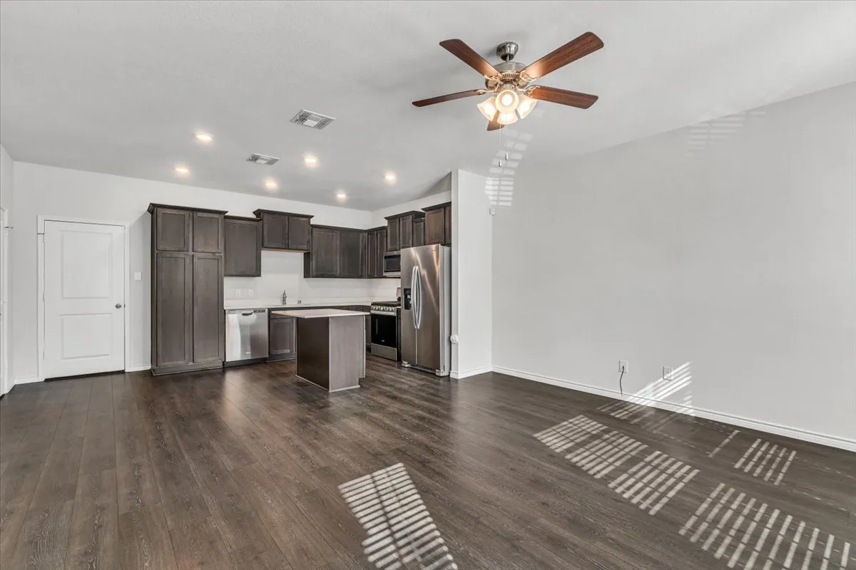 Kitchen featuring dark wood-finish cabinetry, stainless steel appliances, a central island, and recessed lighting
