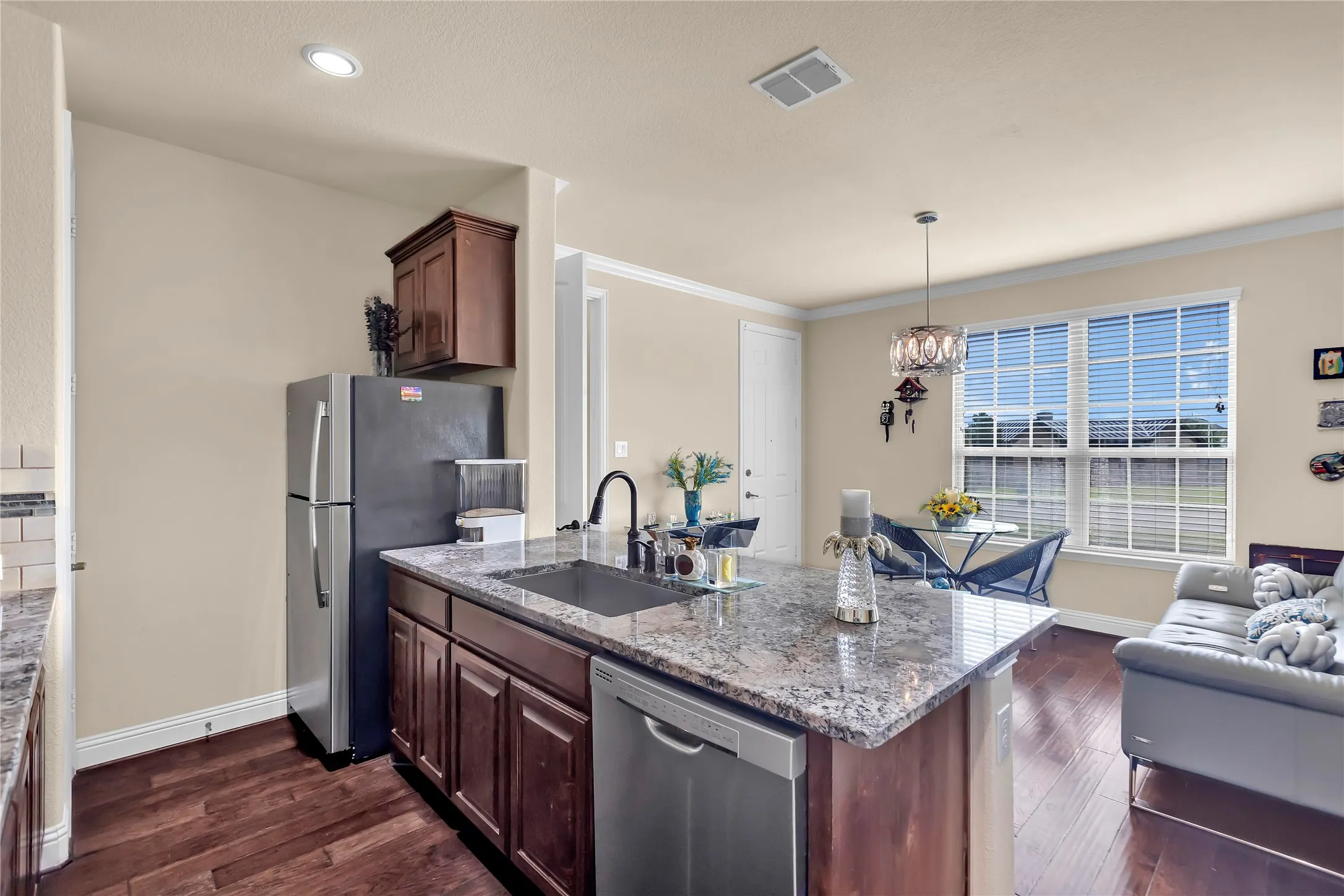 Kitchen island in guest suite with granite countertop, integrated sink, and stainless steel dishwasher and room for bar stools.