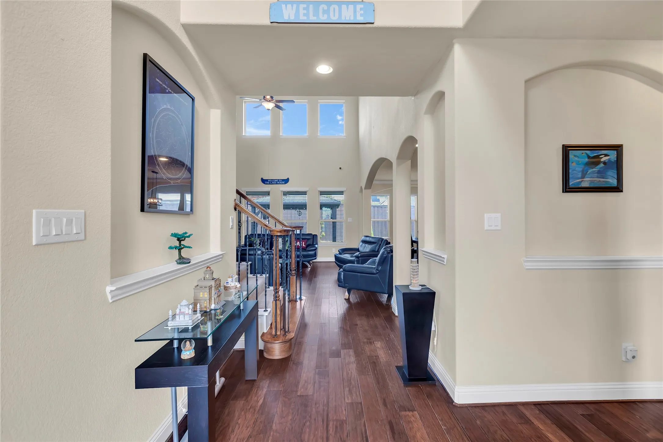 Two-story foyer with high ceilings, wood-finish flooring, an elegant staircase with wood newel posts and metal balusters, and arched doorways