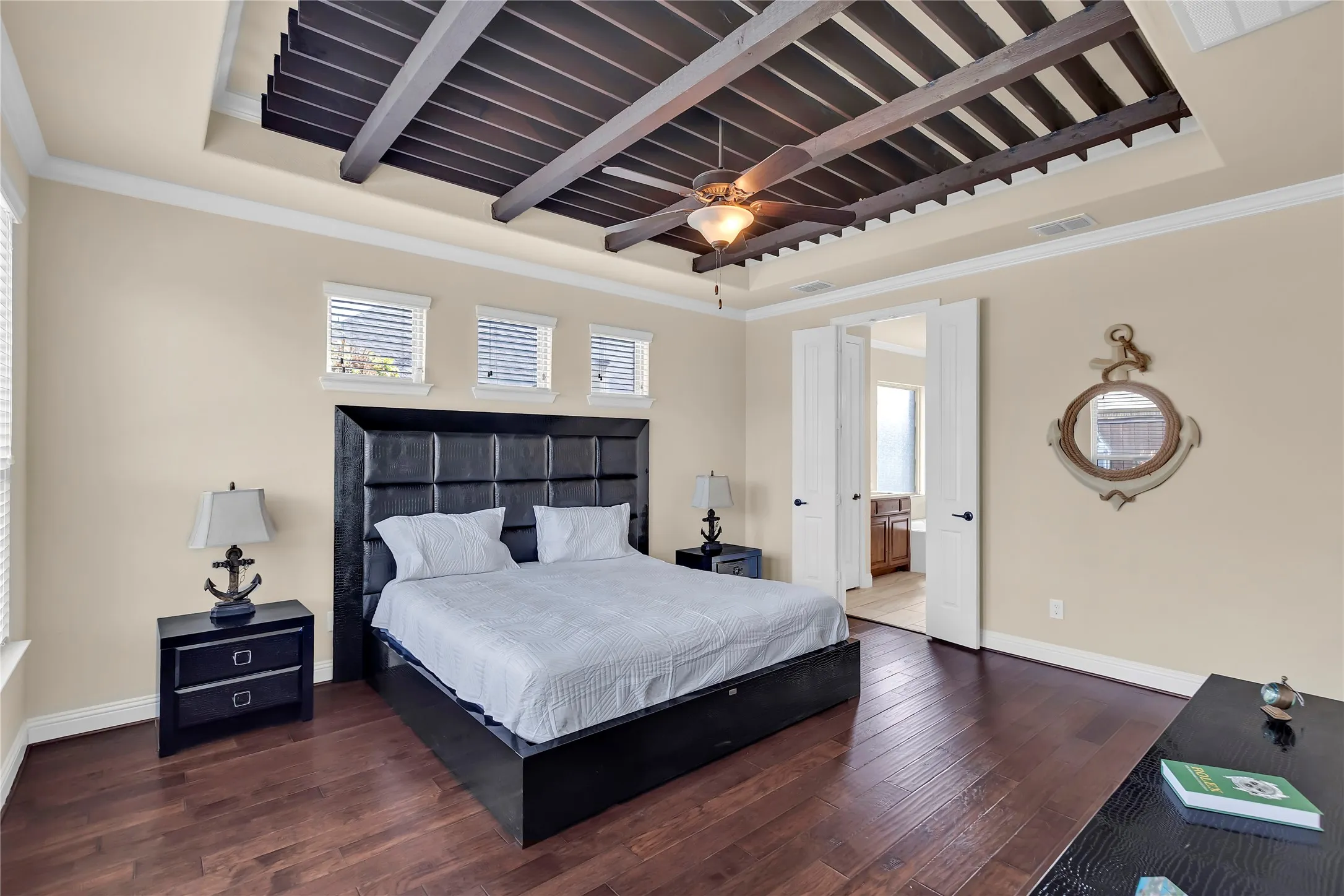 Tray ceiling featuring dark wood-finish beams and a ceiling fan