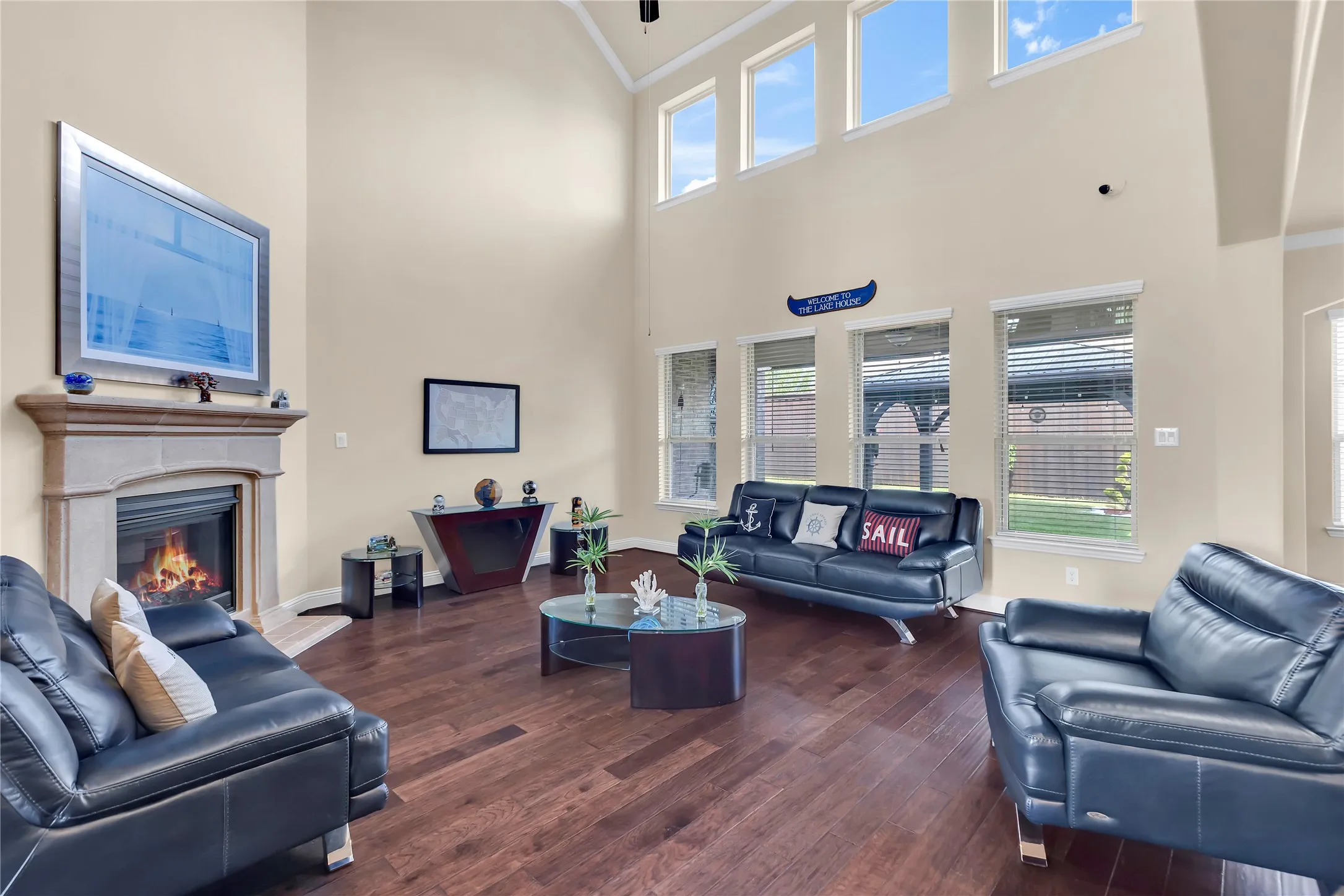 Vaulted ceilings with high transom windows, wood-finish flooring, stone-clad fireplace, and multiple ground-level windows