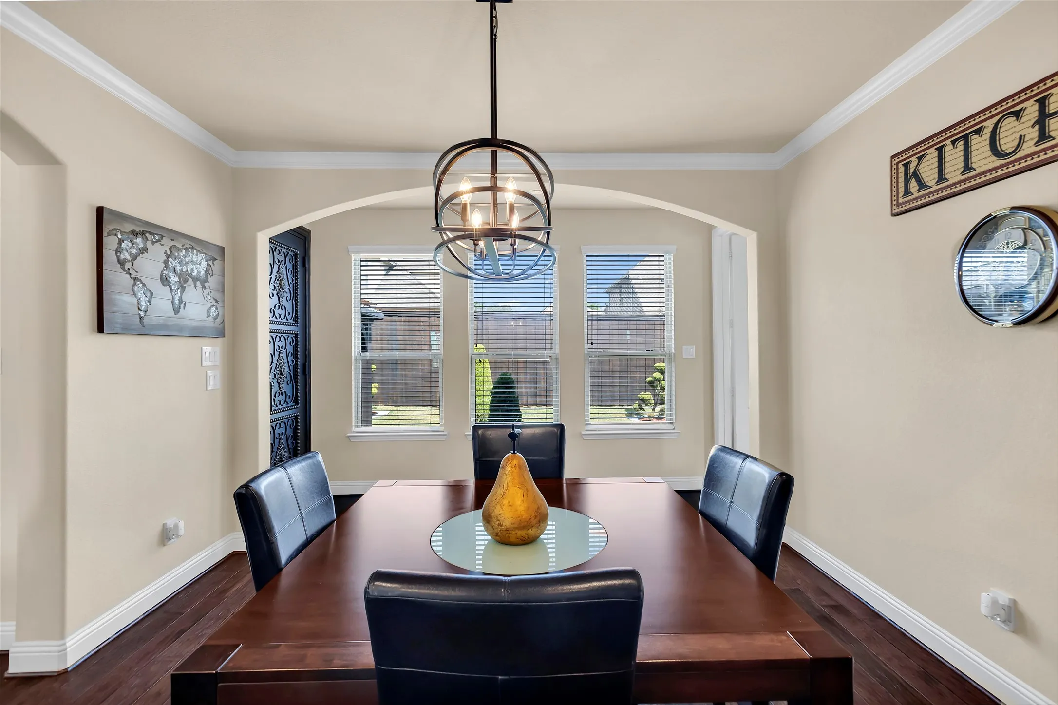 Archway entry with a contemporary orb chandelier, dark wood-finish flooring, and white crown molding