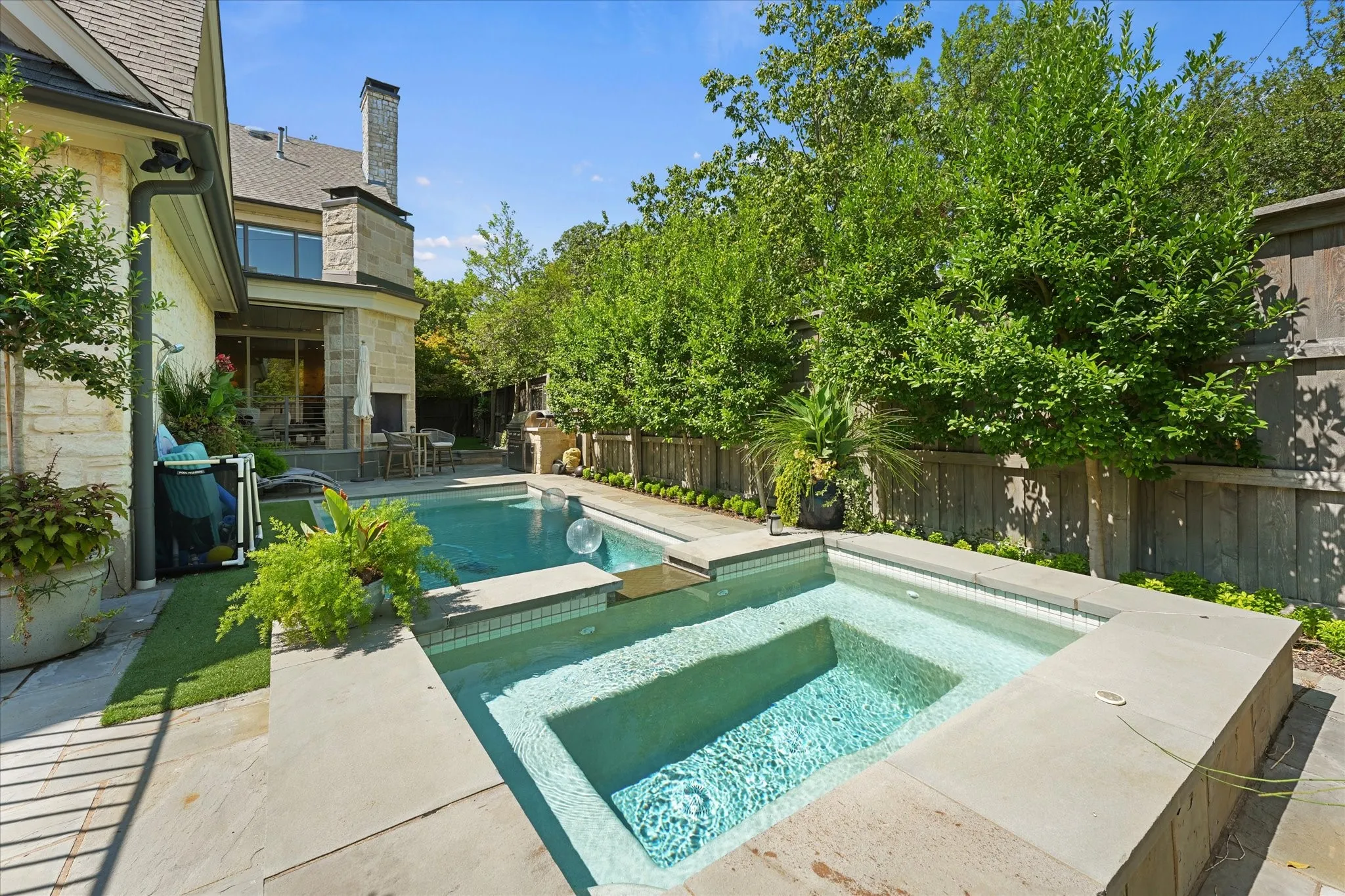 Raised spa with submerged bench seating adjoins the rectangular pool.