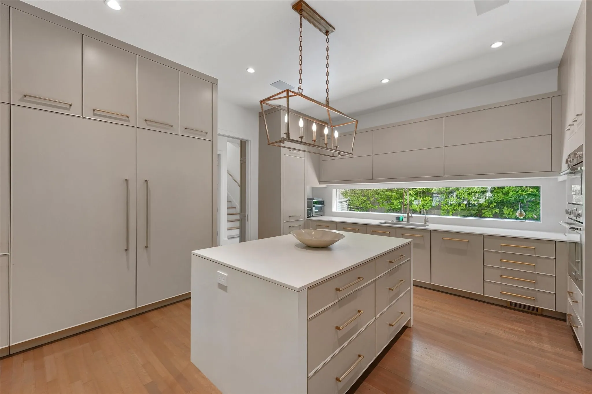 A rectangular lantern pendant hangs above the island, with paneled Thermador  refrigerator and freezer.
