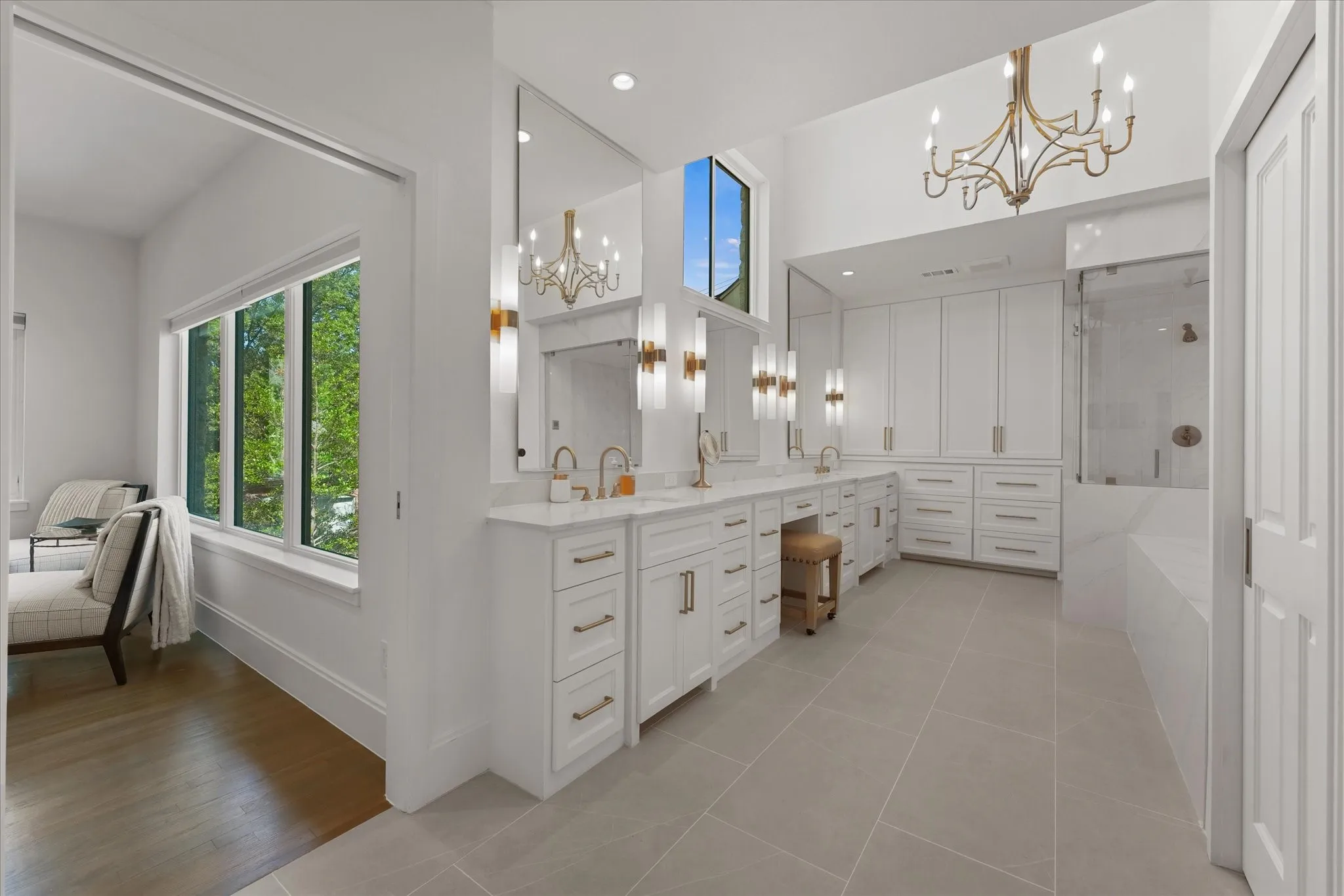 A double vanity pairs tall mirrors and vertical sconces with jetted tub with steam shower.