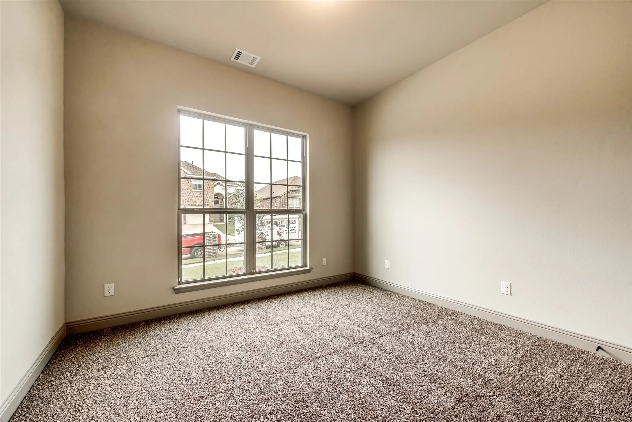 Carpeted flooring, neutral wall tones, and a multi-pane window