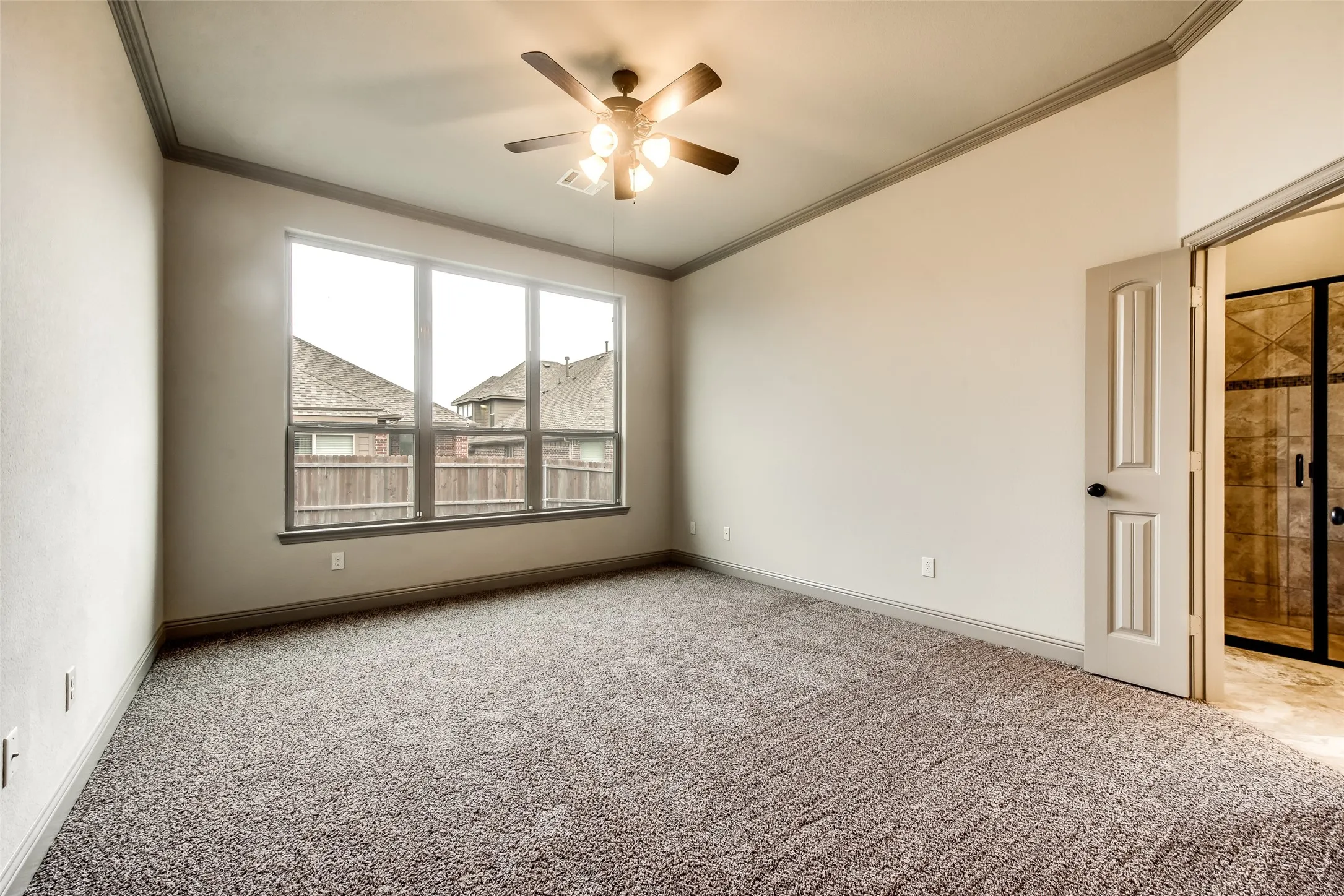 Expansive room featuring plush carpeting, a large multipane window, and a ceiling fan with integrated lighting