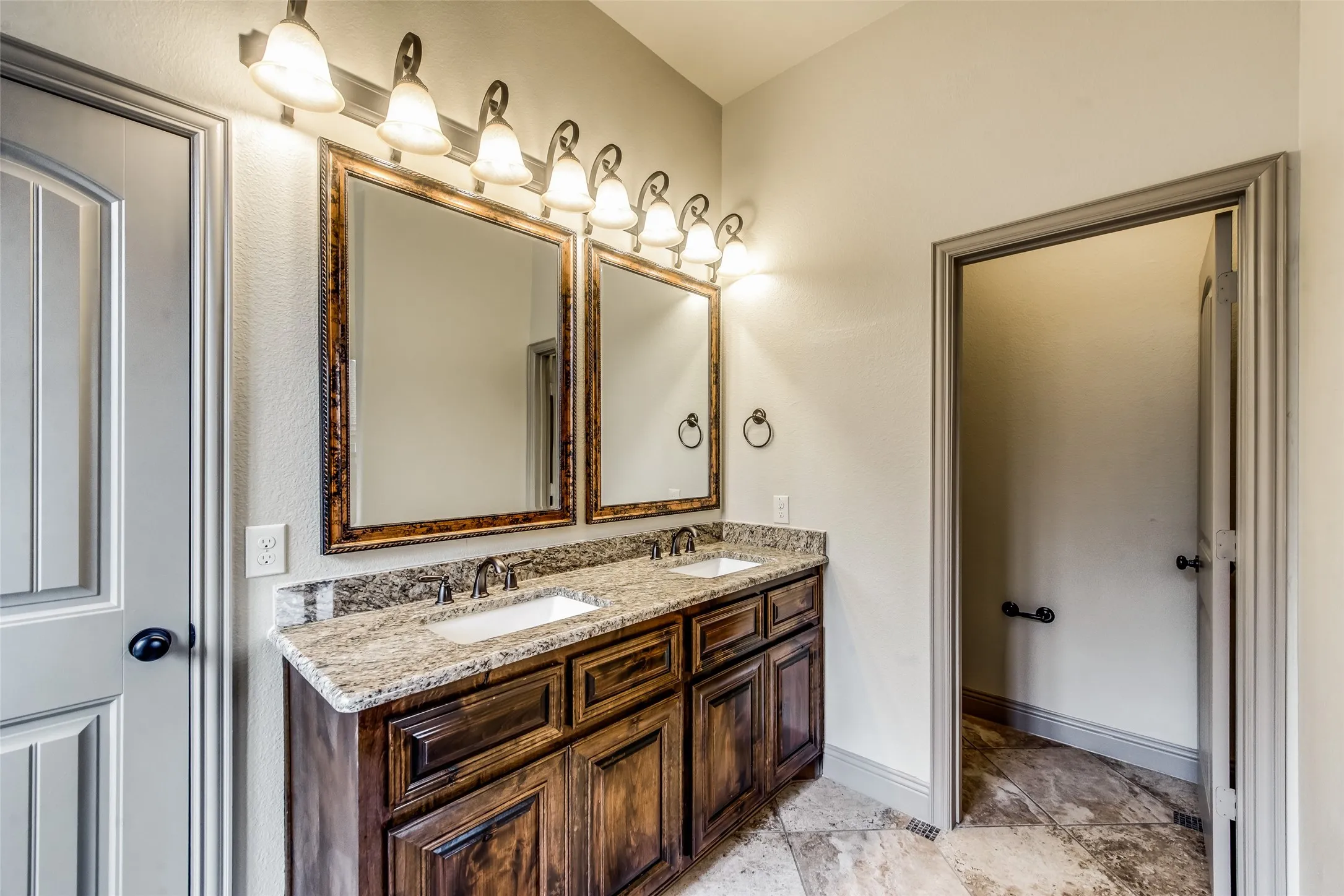 Dual vanity with undermount sinks, stone countertops, and dark wood cabinetry