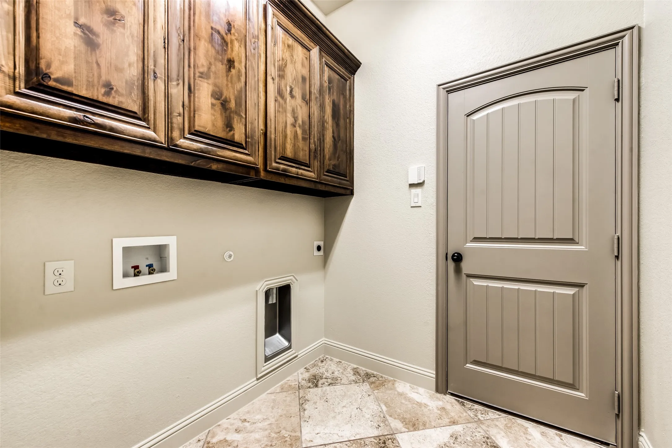 Laundry area featuring wood cabinetry, wall hookups for appliances, and tile flooring