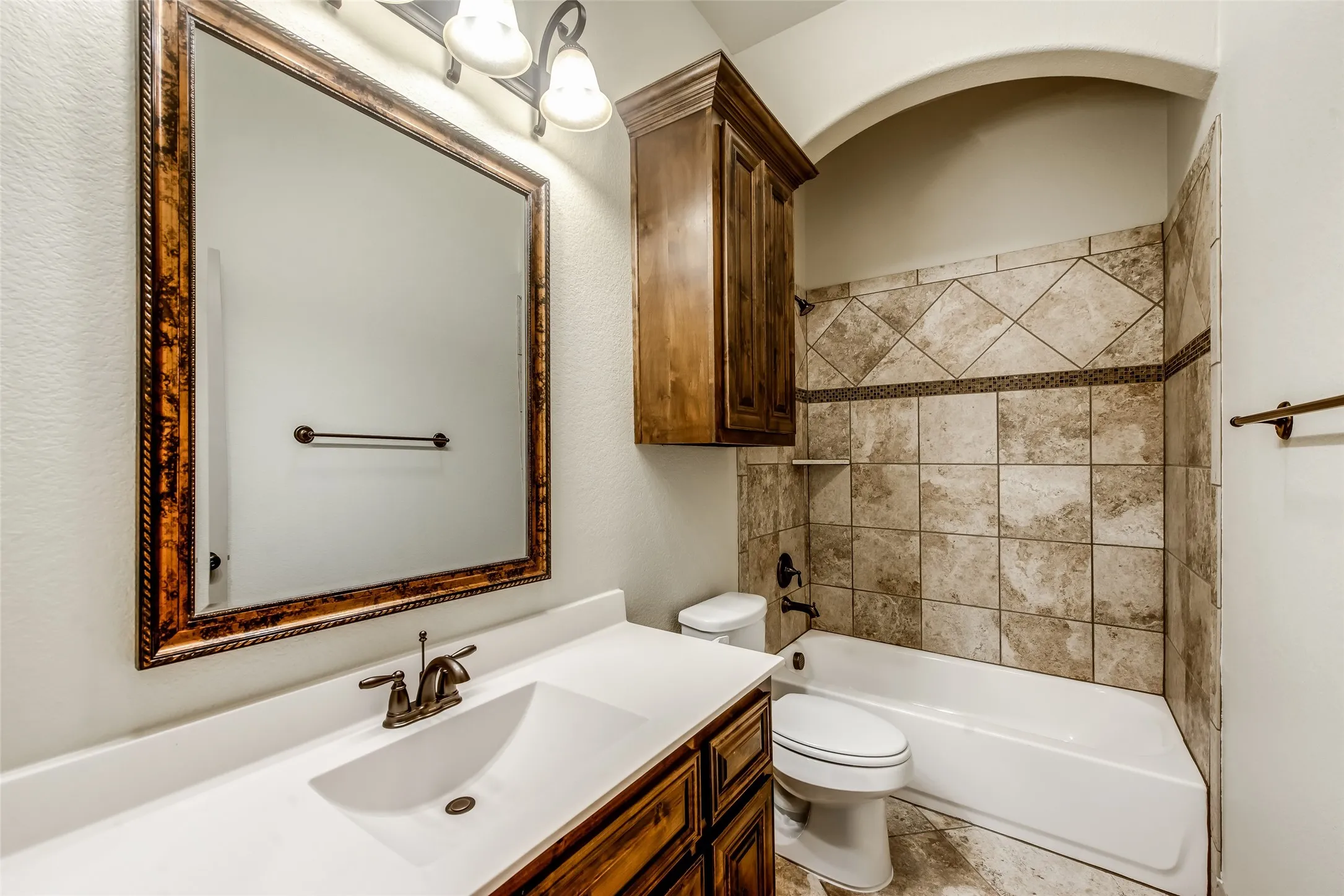 Bathroom featuring a single vanity with an integrated sink, bronze-finish faucet, and coordinating framed mirror