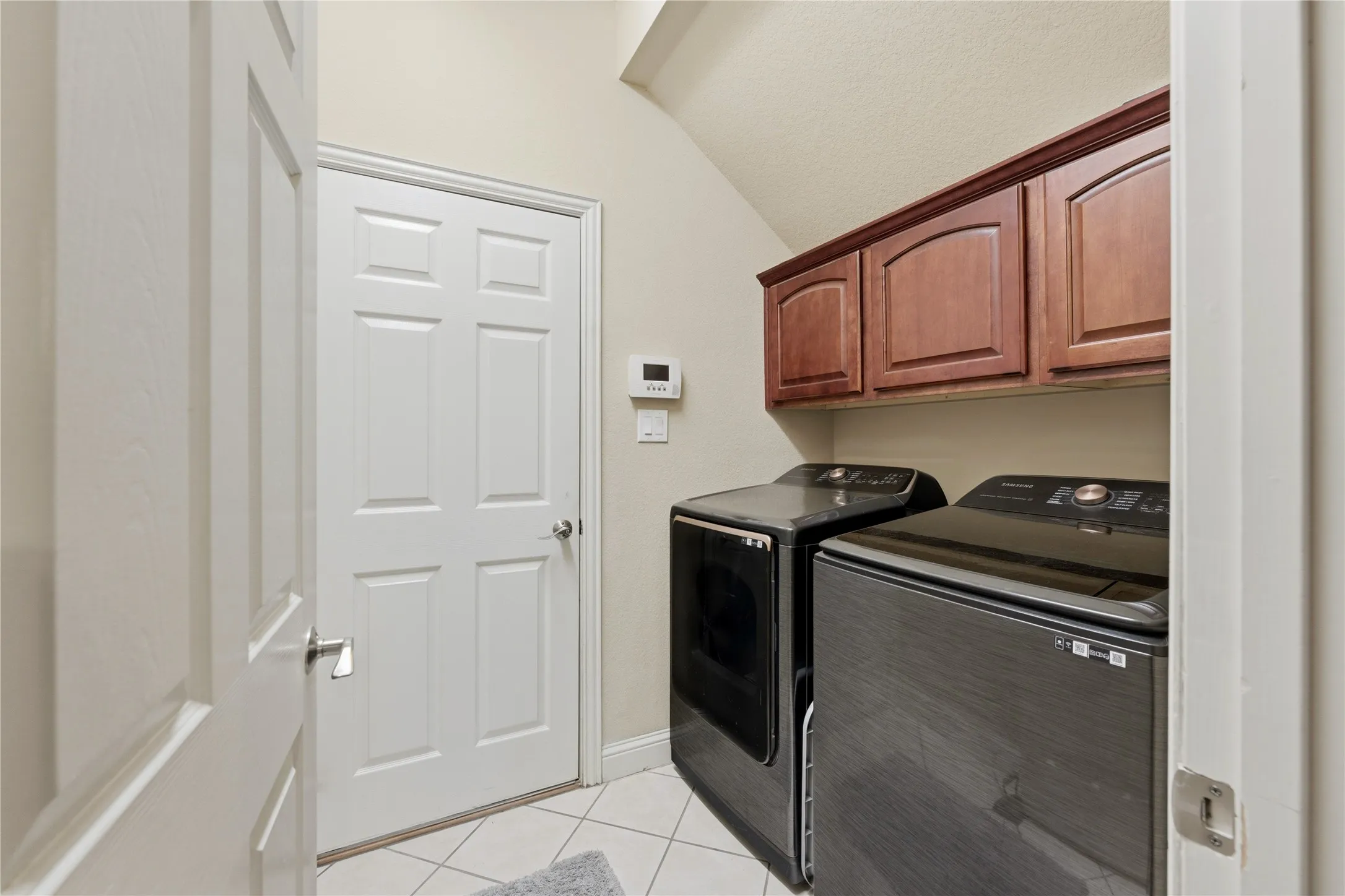 Laundry area featuring wood-finish cabinetry