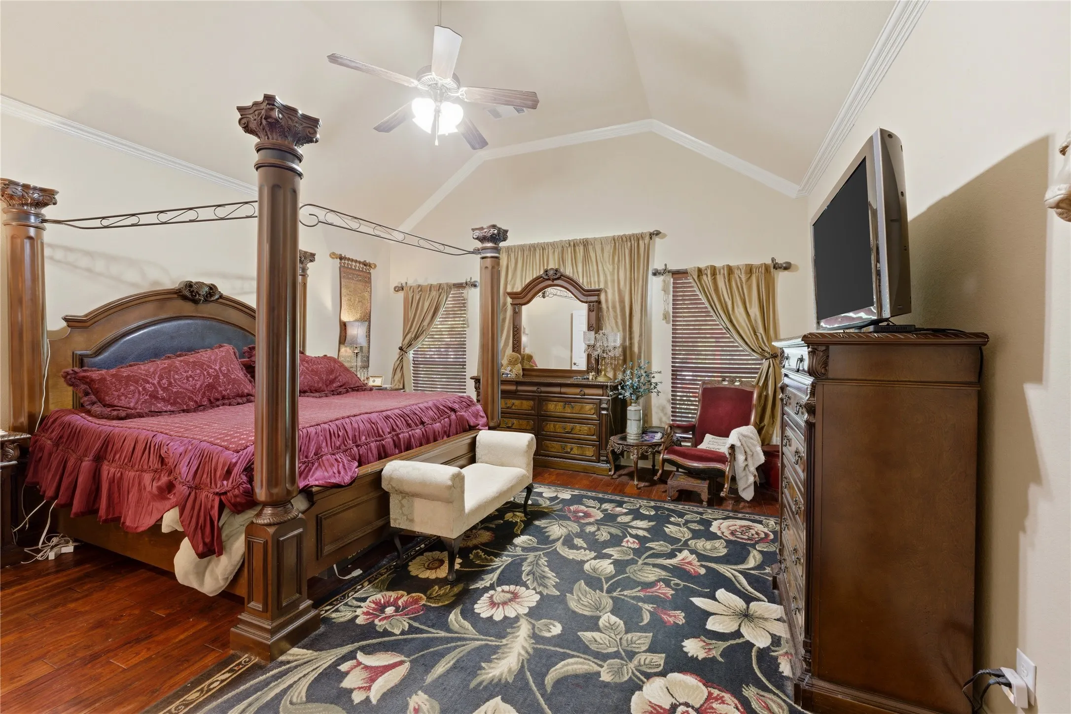Vaulted ceiling with crown molding, wood-finish flooring, and a ceiling fan with integrated lighting