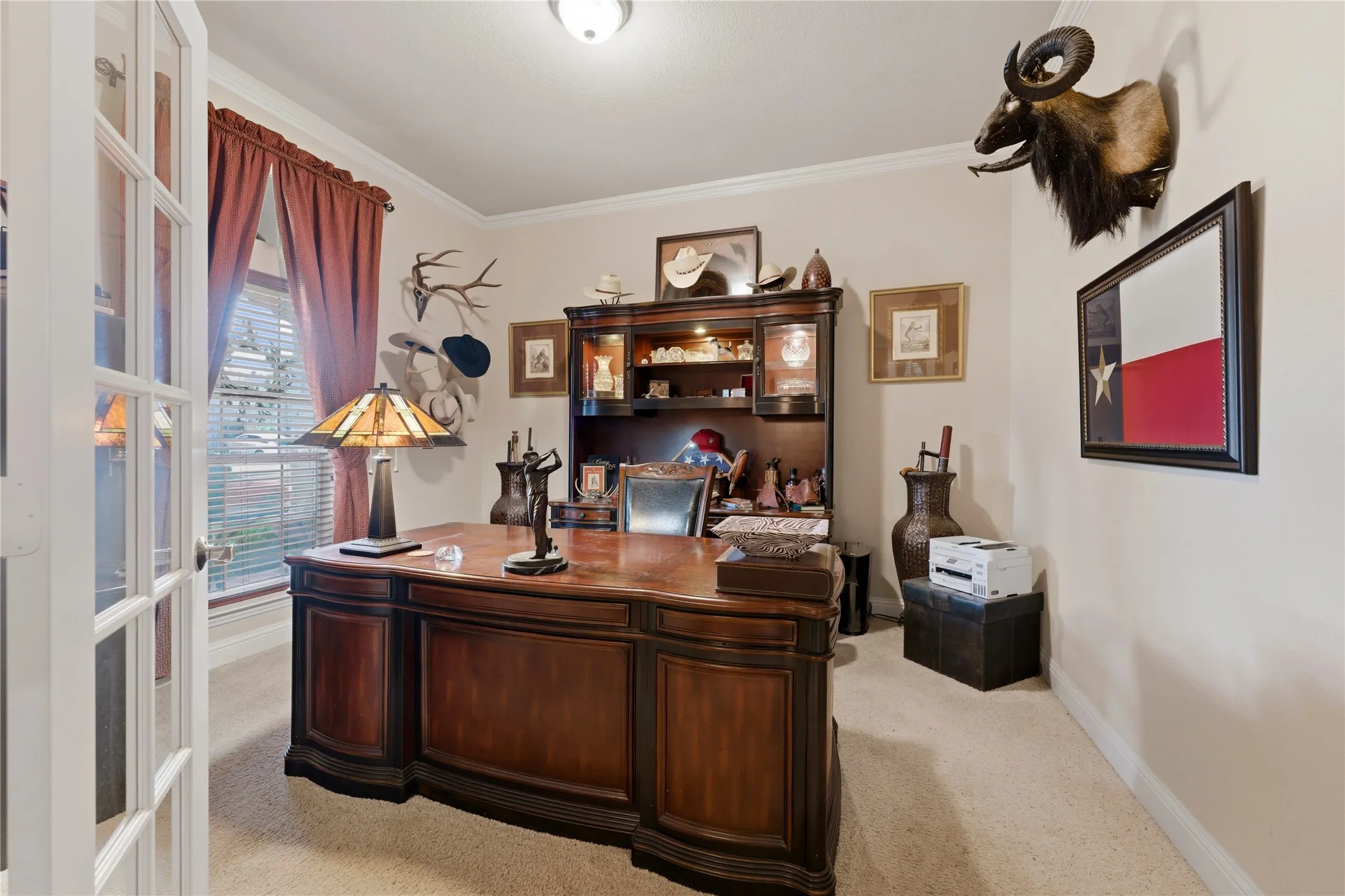 Private office space featuring French doors, carpet flooring, crown molding, and a window with horizontal blinds
