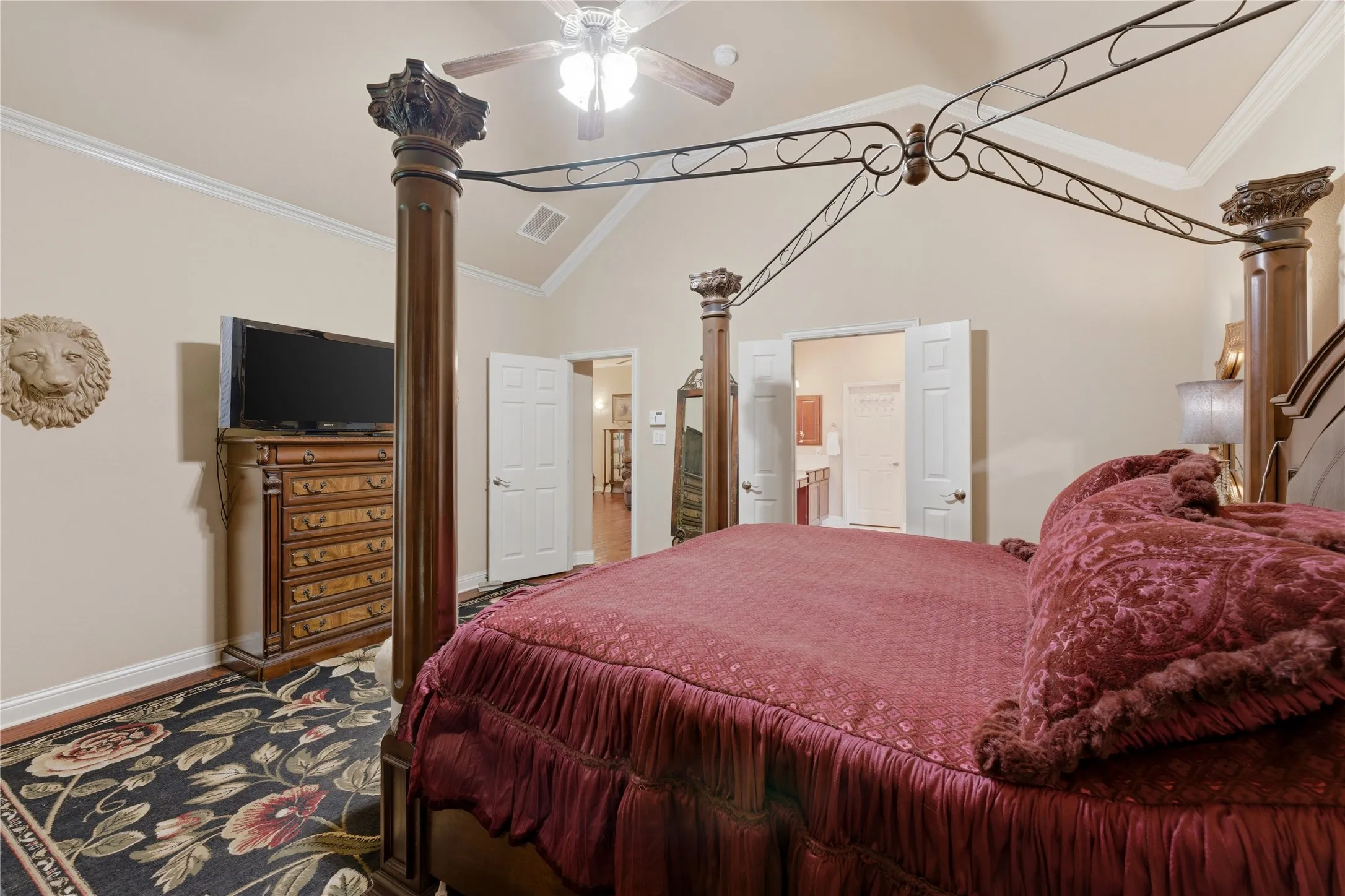 Vaulted ceiling with crown molding, ceiling fan, and double-door entry