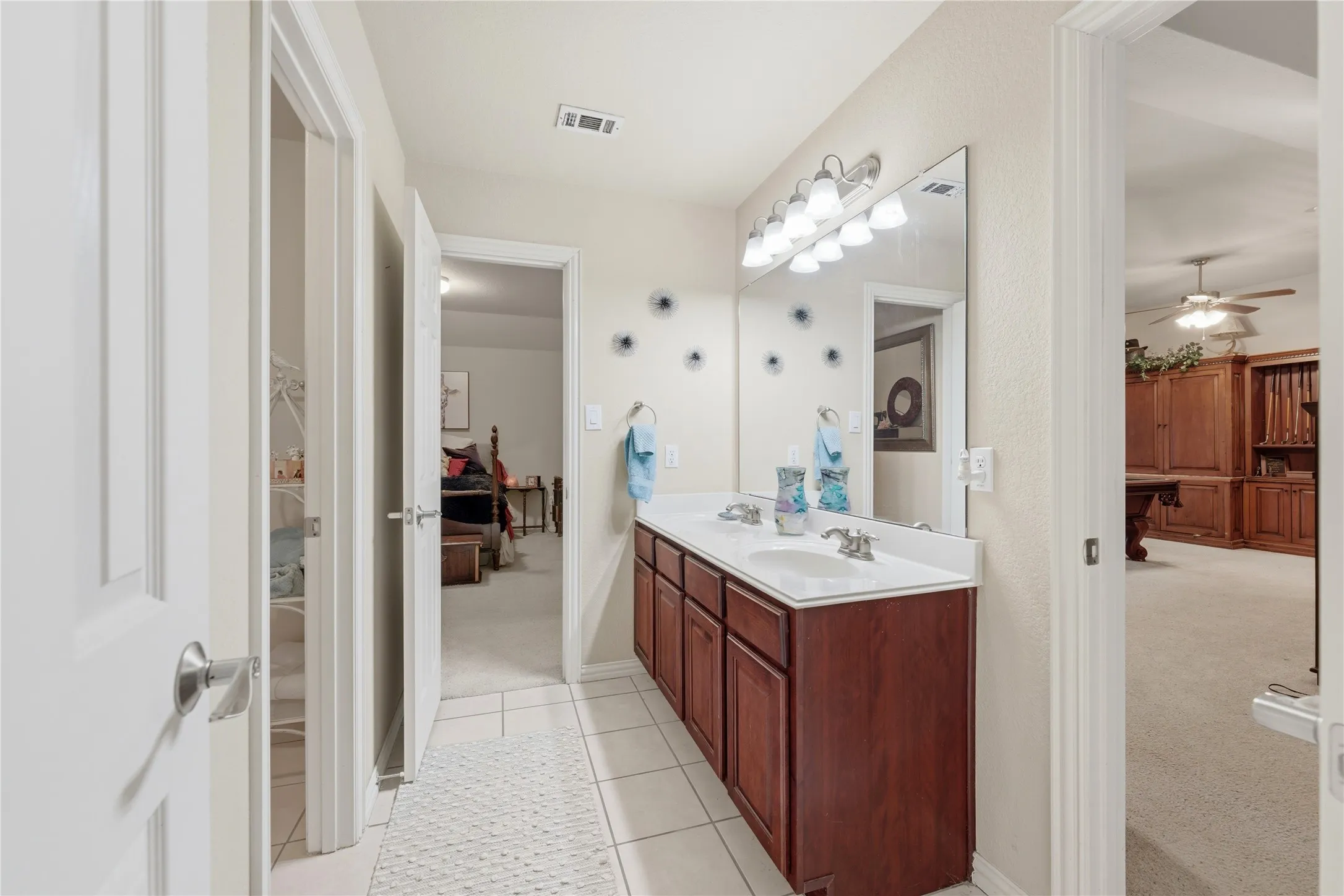 Dual vanity with integrated sinks, expansive mirror, polished chrome fixtures, and wood-finish cabinetry