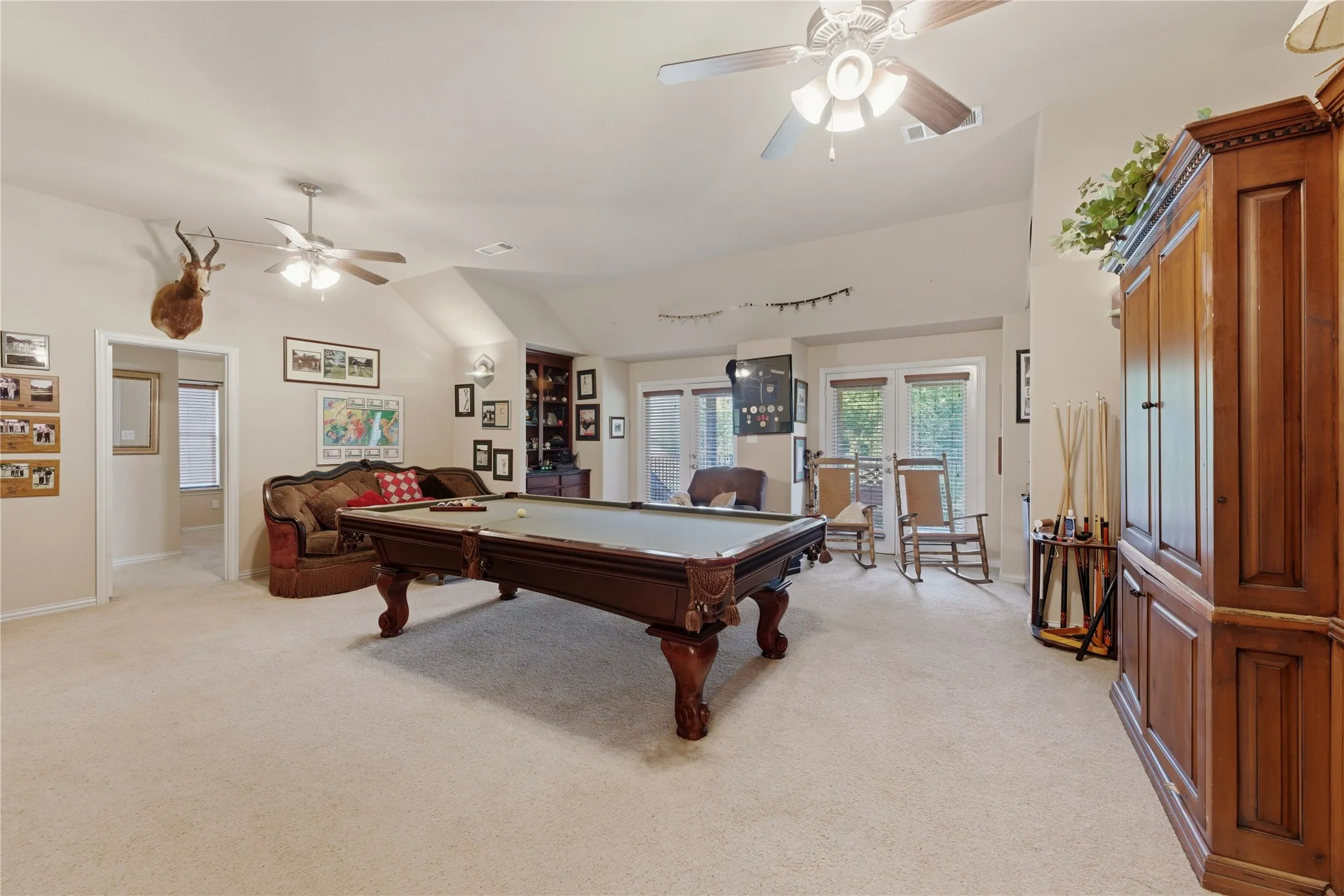 Spacious room featuring vaulted ceilings, neutral carpeting, and multiple ceiling fans