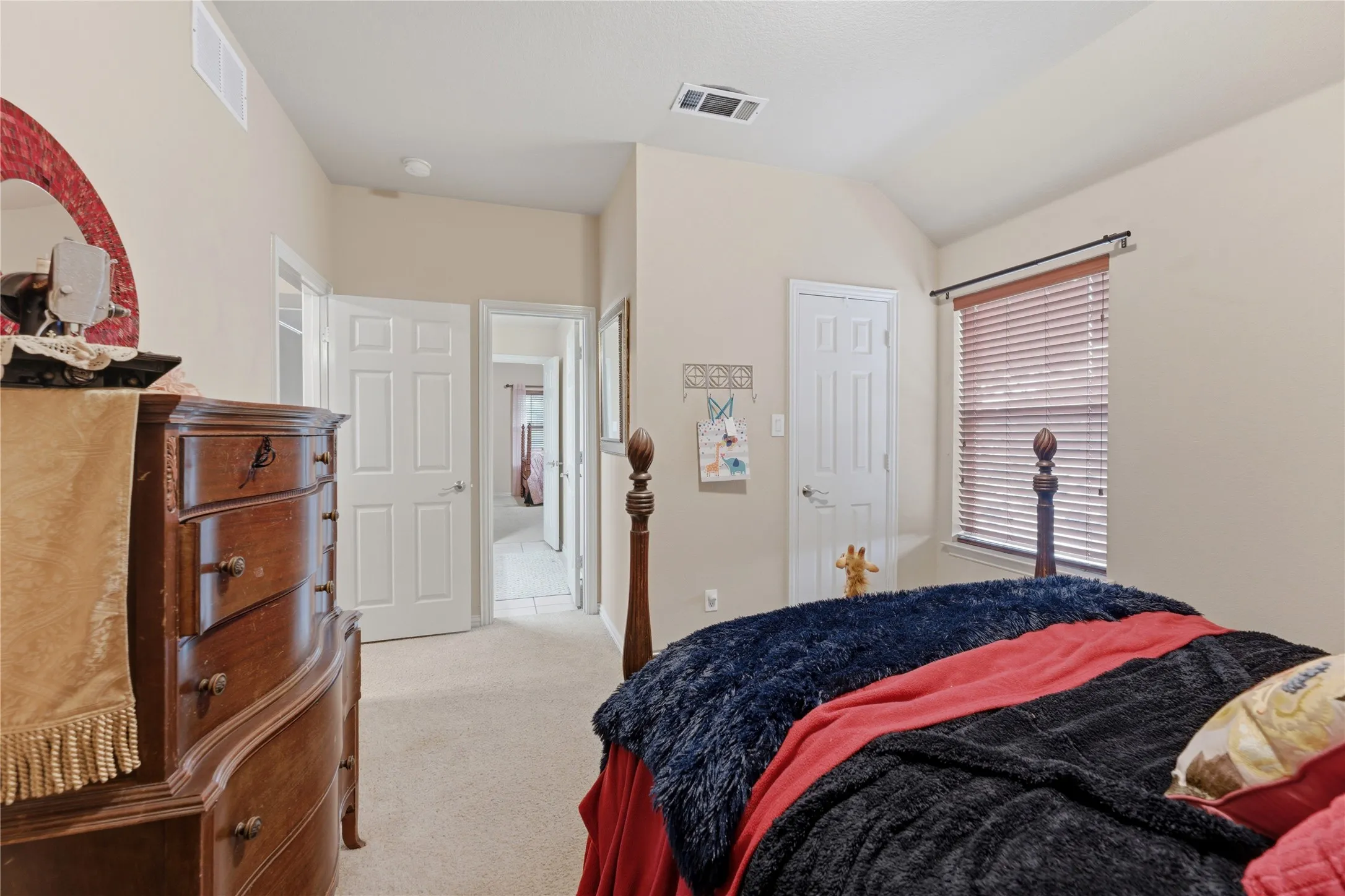 Carpeted flooring, vaulted ceiling, neutral wall tones, and white interior doors