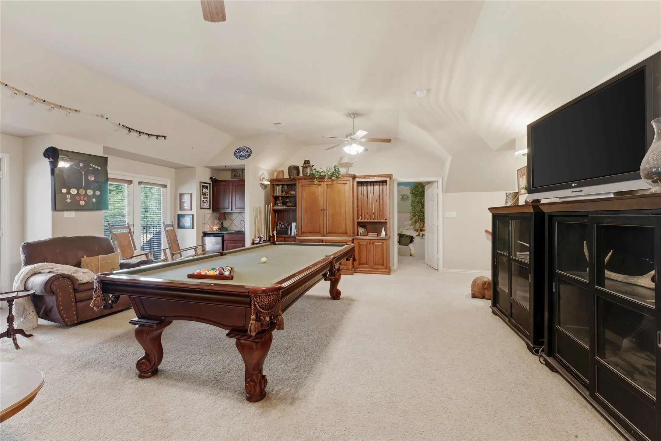 Spacious room featuring vaulted ceilings, ceiling fans, and light-toned carpeting