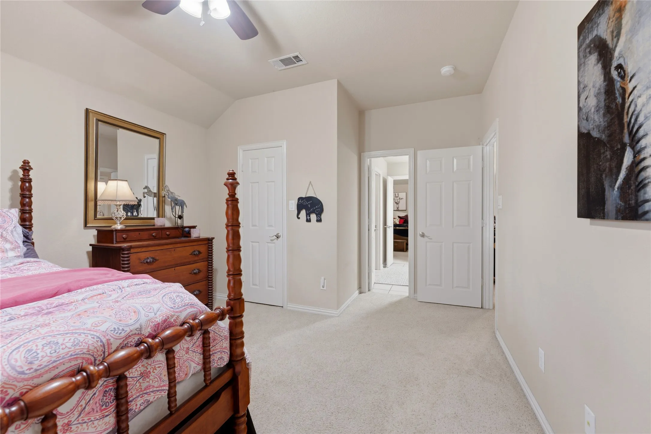 Vaulted ceiling accentuates the spacious room with neutral carpeting and a ceiling fan