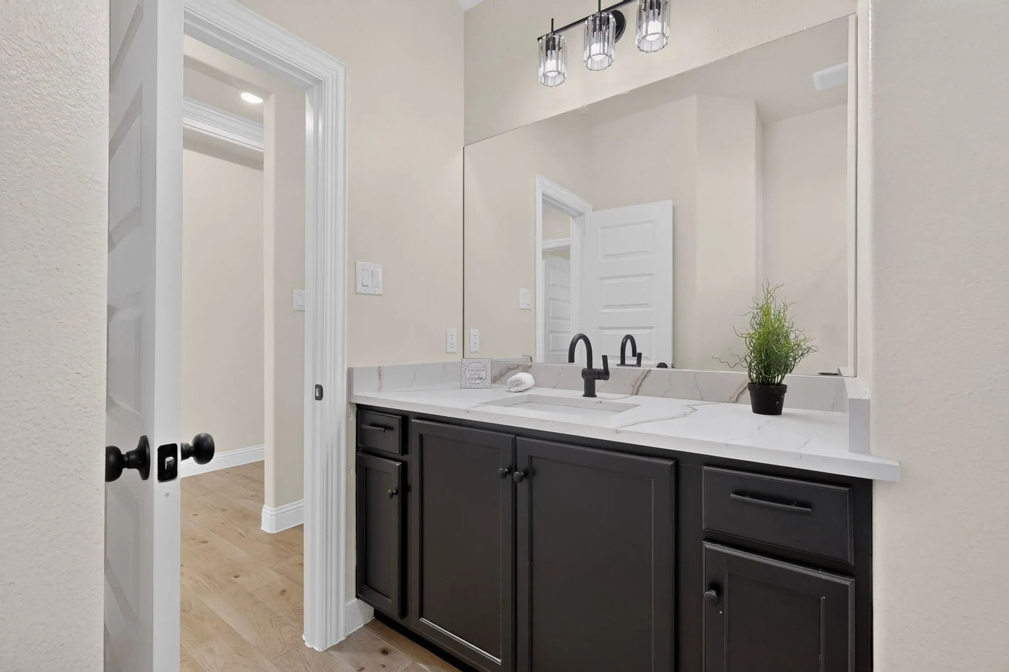 Vanity with dark cabinetry and white countertop, undermount sink, and matte black faucet