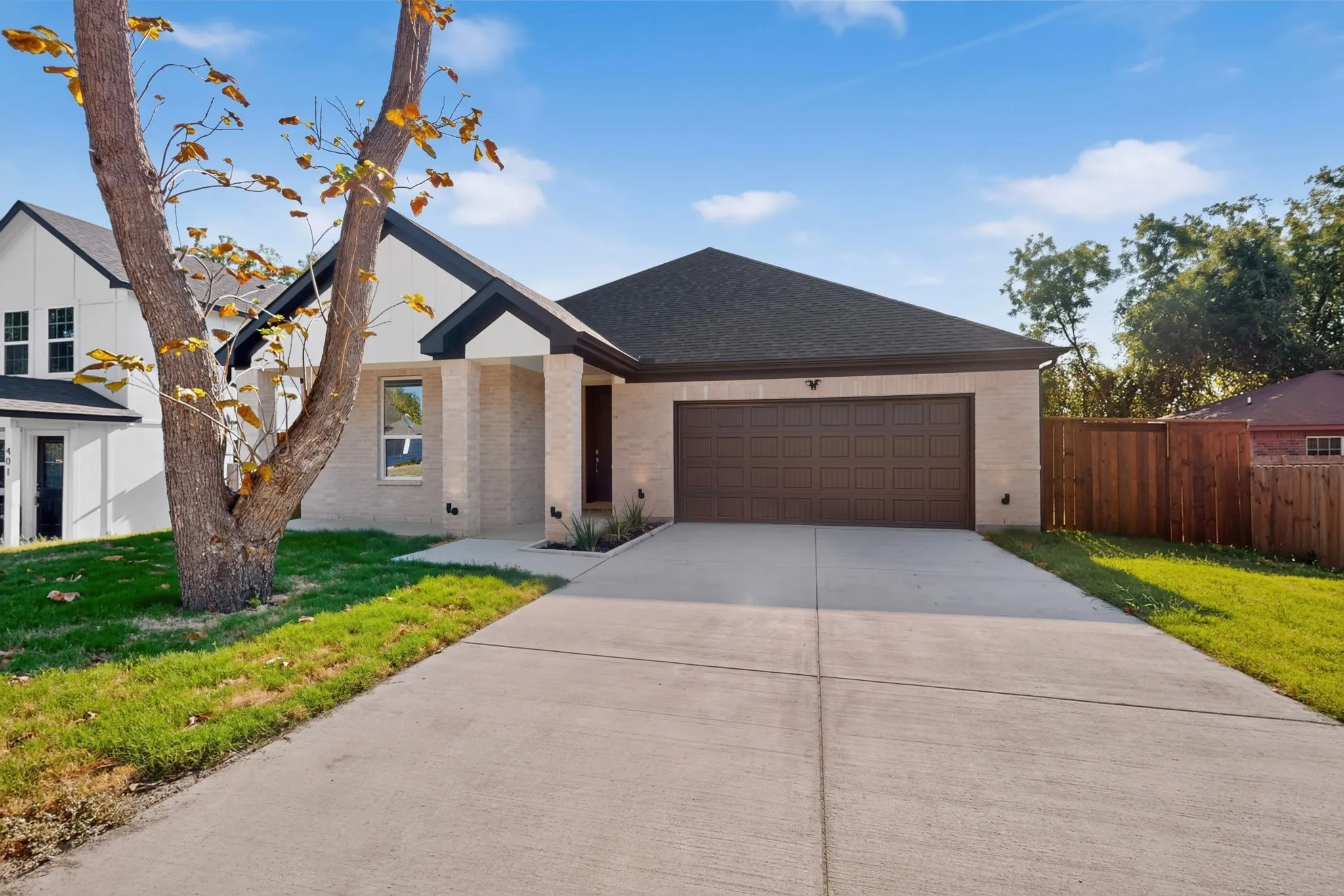 Contemporary single-story residence with a light-toned brick facade, dark roofing, and a two-car garage