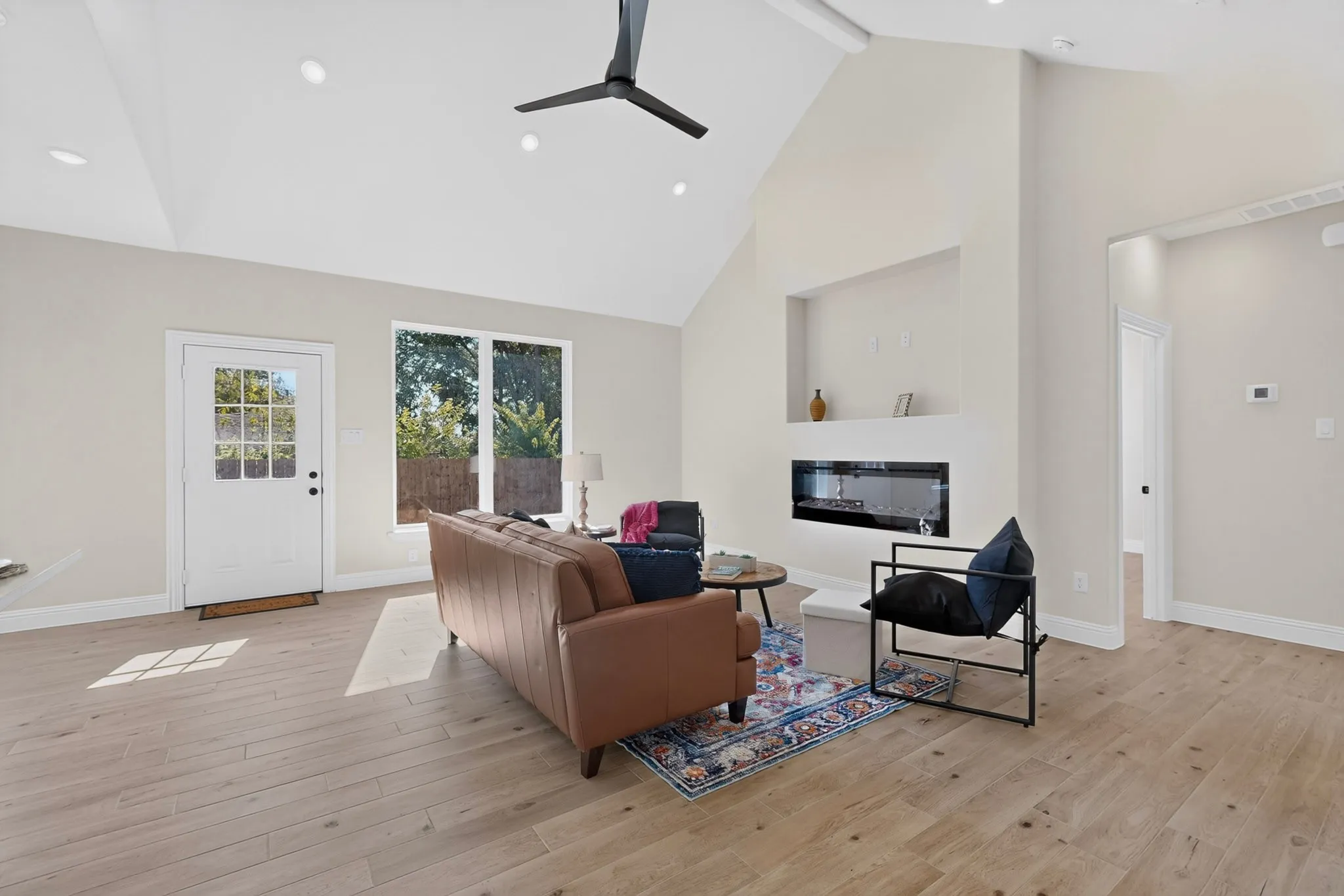 Vaulted ceiling living area featuring wood-finish flooring, recessed lighting, and a modern linear fireplace
