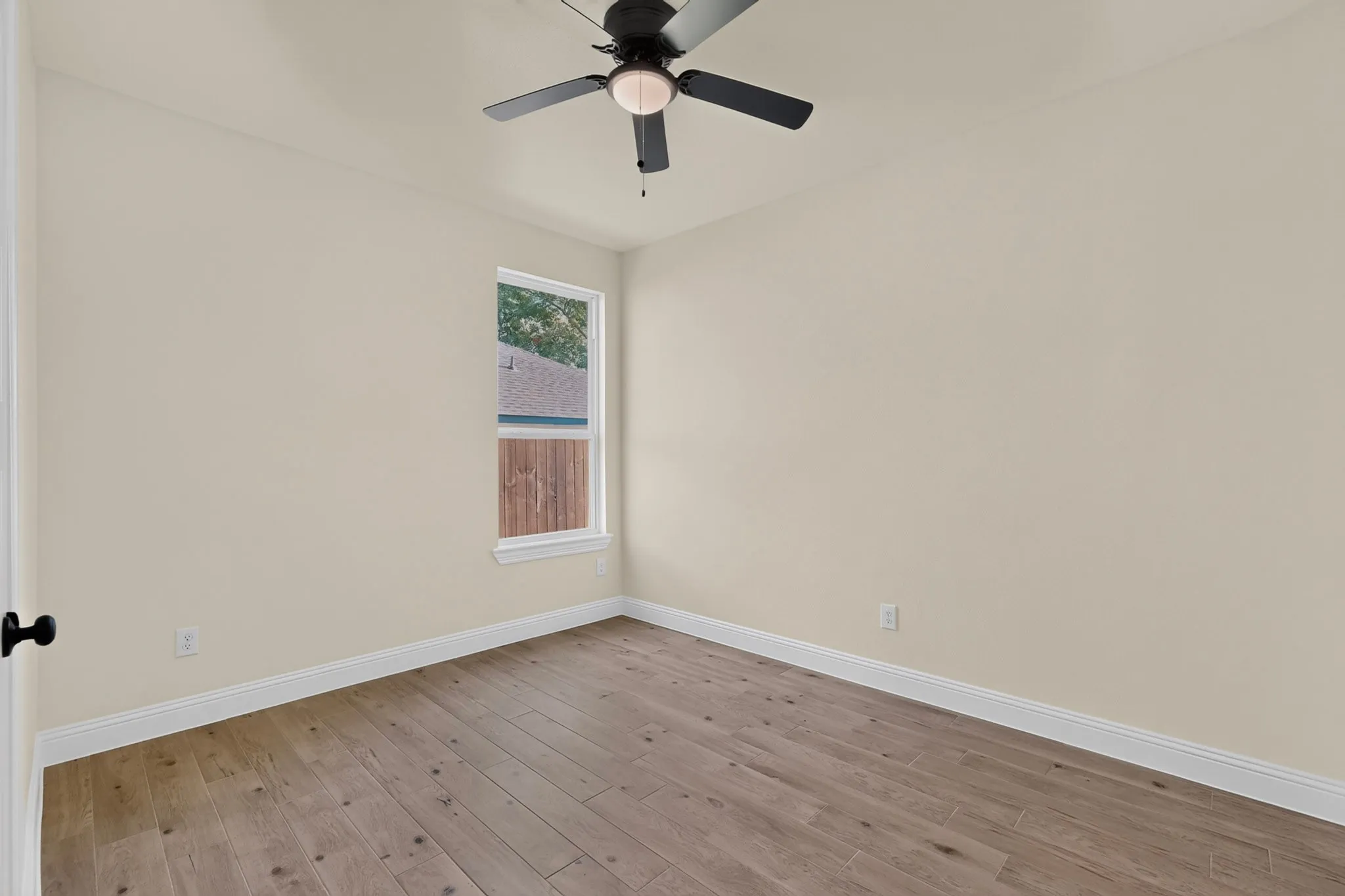 Wood-finish flooring, single window, white trim, ceiling fan, and neutral wall tones