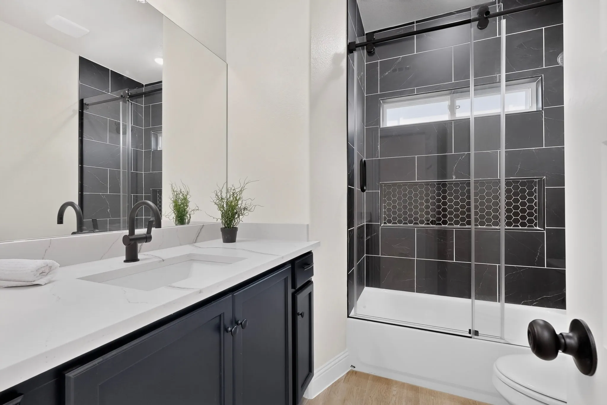 White quartz countertop with dual integrated sinks, matte black faucets, and dark wood-finish cabinetry