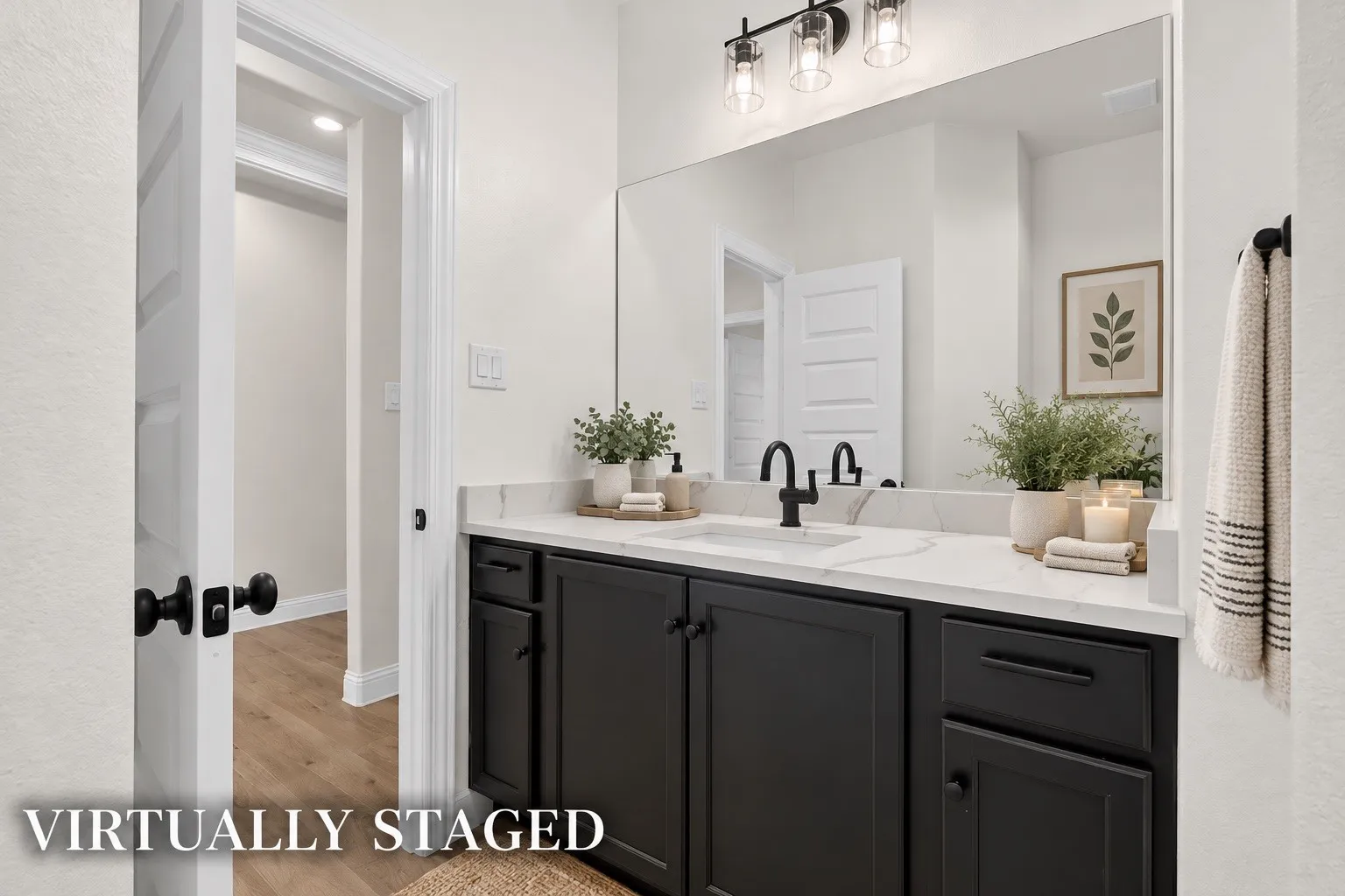 Vanity with dark cabinetry and a light-toned countertop, large mirror, and three-light fixture