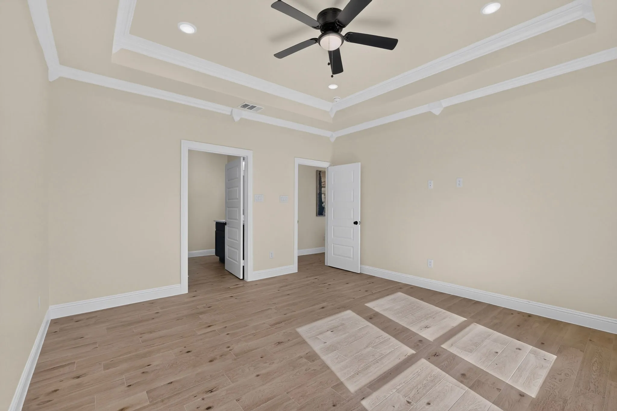 Wood-finish flooring, tray ceiling with recessed lighting, ceiling fan, and white trim throughout