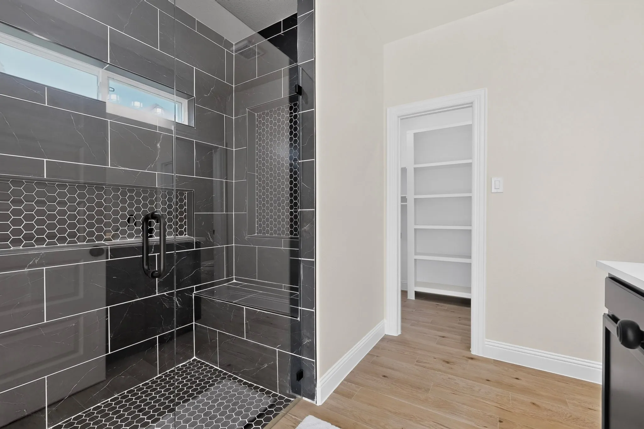 Walk-in shower with dark tile and hexagonal accenting