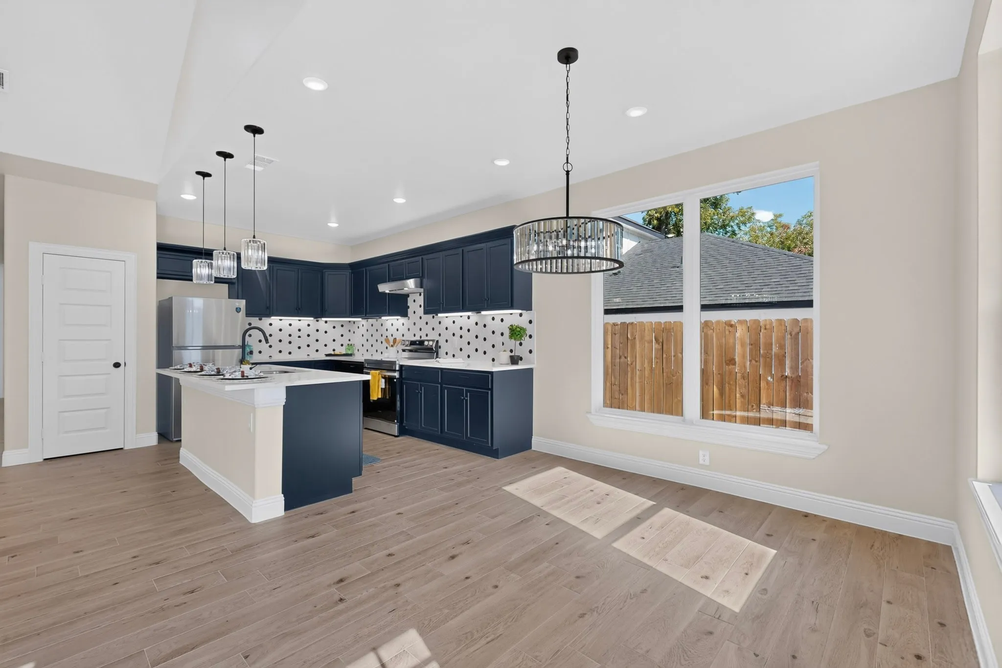 Open-concept kitchen and dining area featuring wood-finish flooring, dark cabinetry, and a kitchen island with pendant lighting
