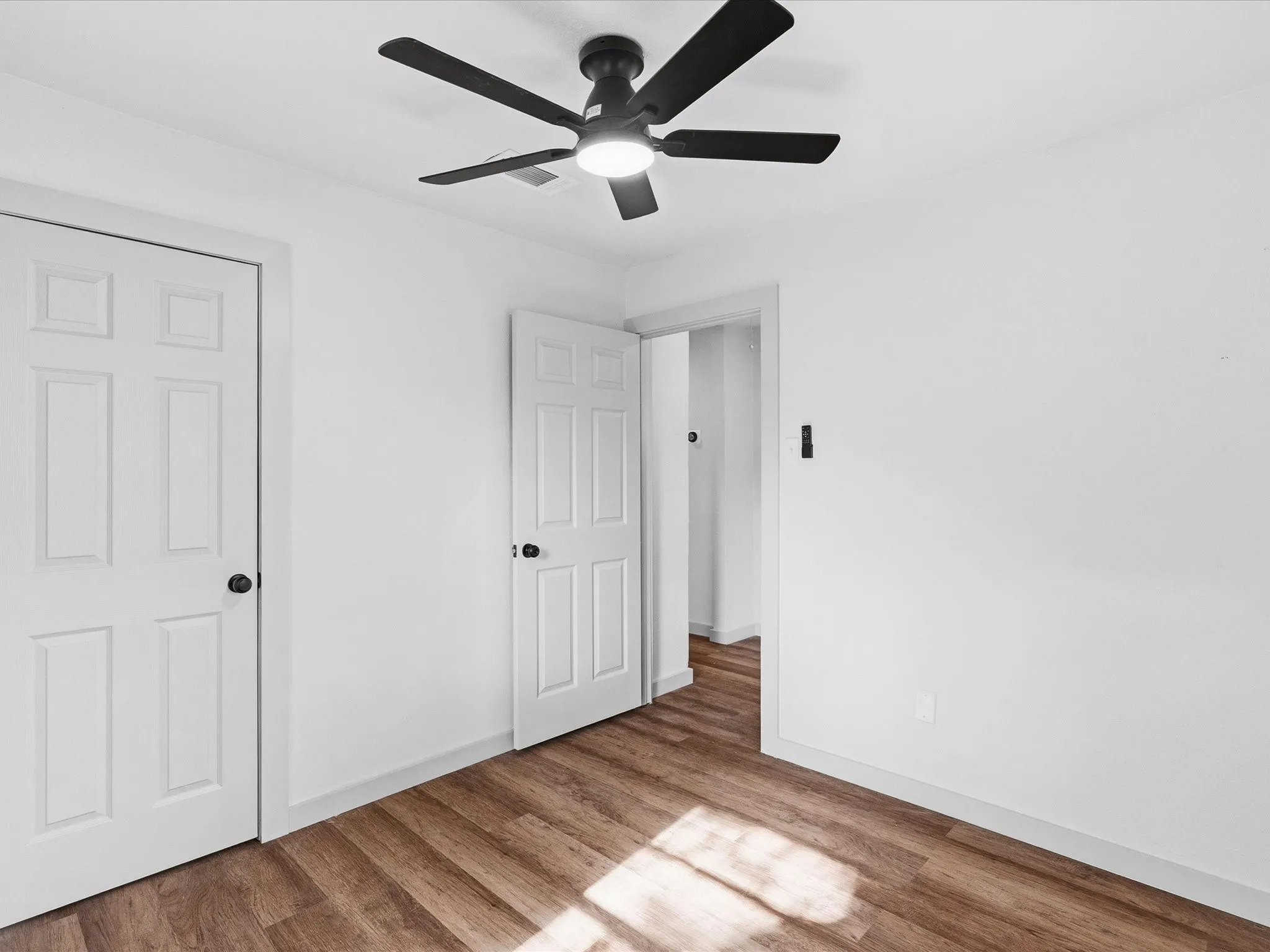 Wood-finish flooring with crisp white walls and white paneled doors