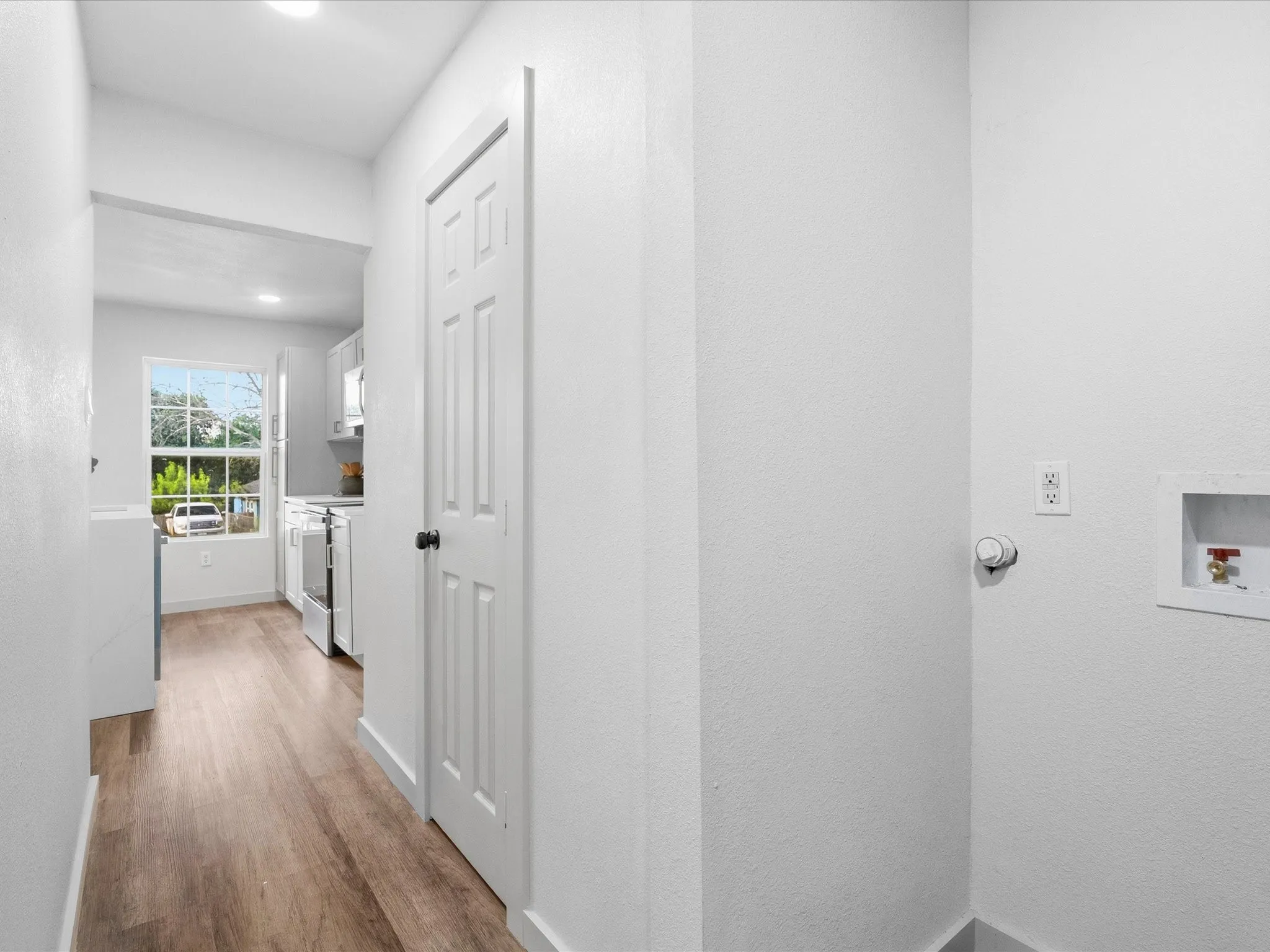 Wood-finish flooring throughout, white paneled interior doors, recessed lighting, and a dedicated laundry area