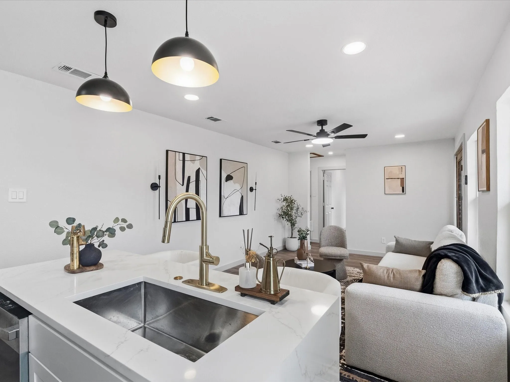 Kitchen island with a stainless steel undermount sink and gold-tone faucet, complemented by two black pendant lights