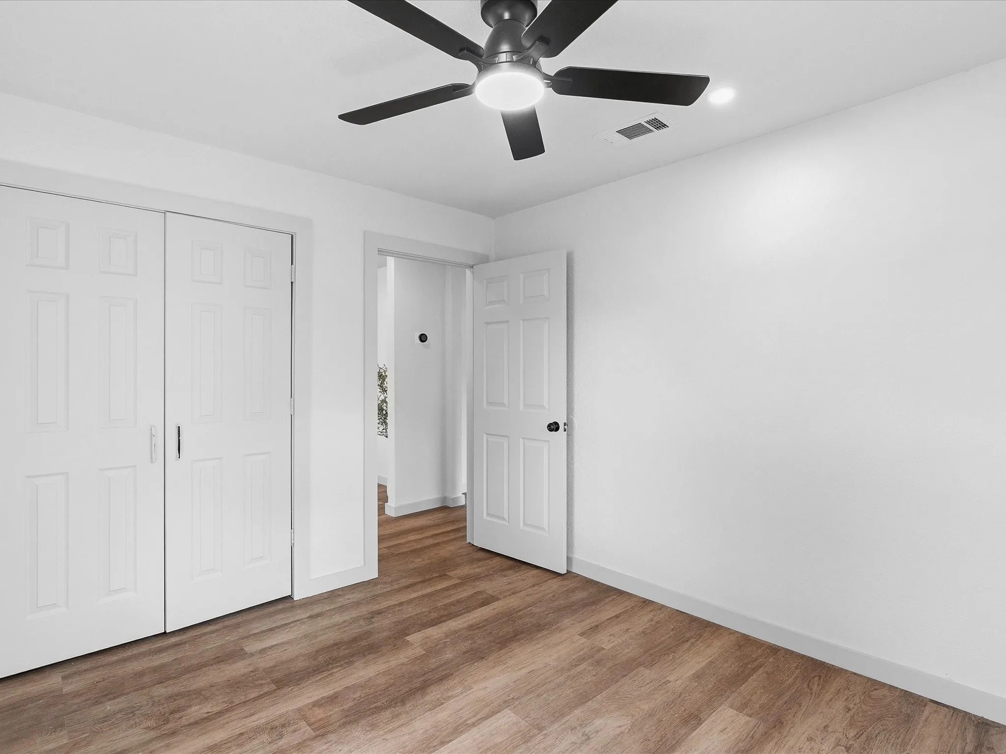 Wood-finish flooring, white walls, and a contemporary ceiling fan with integrated lighting